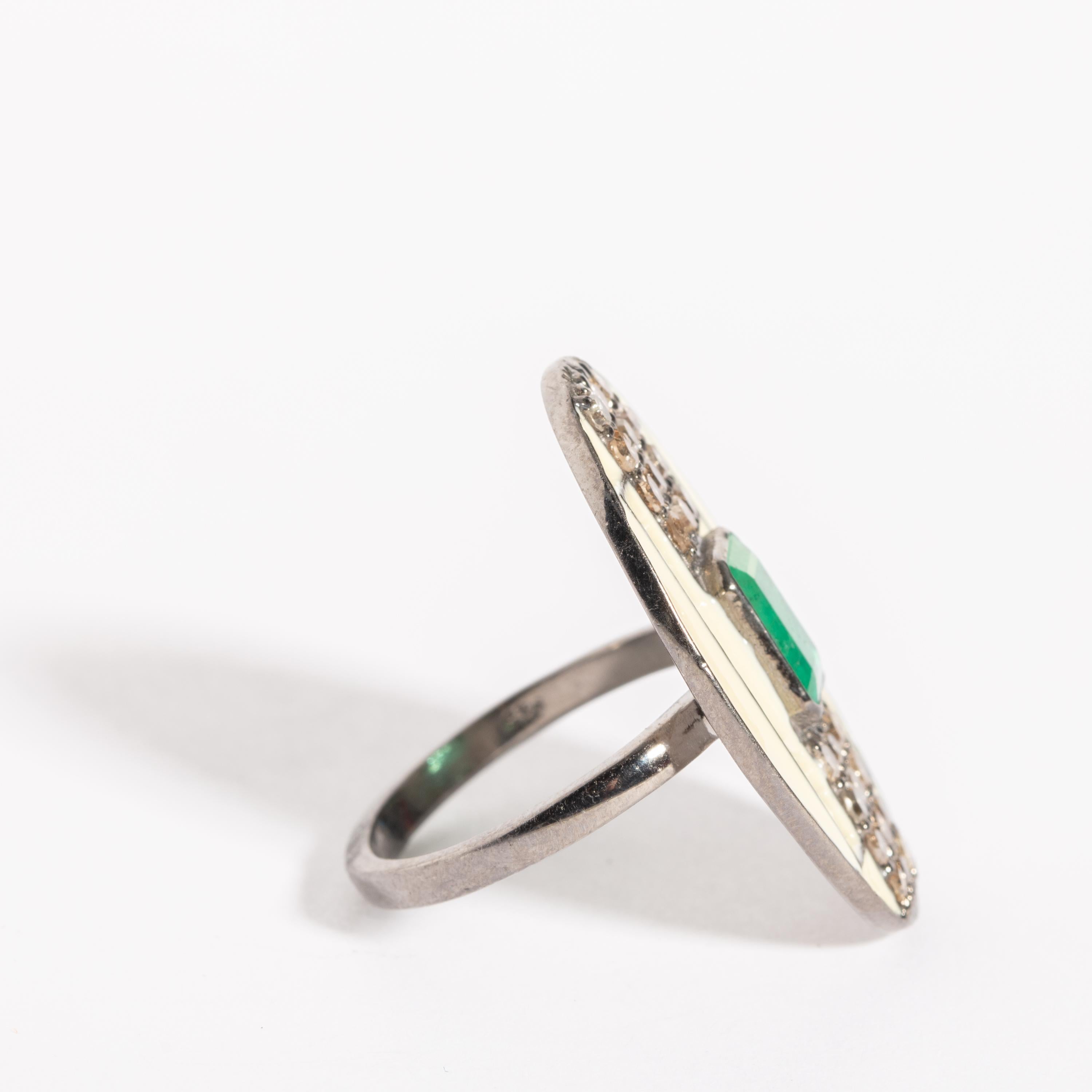 In an Art Deco design, a white enamel and sterling silver ring with an emerald-cut center stone emerald  with brilliant-cut diamonds.  Weight of diamonds is .81 carats, emerald is 1.15 carats.  Ring size is 7.25.