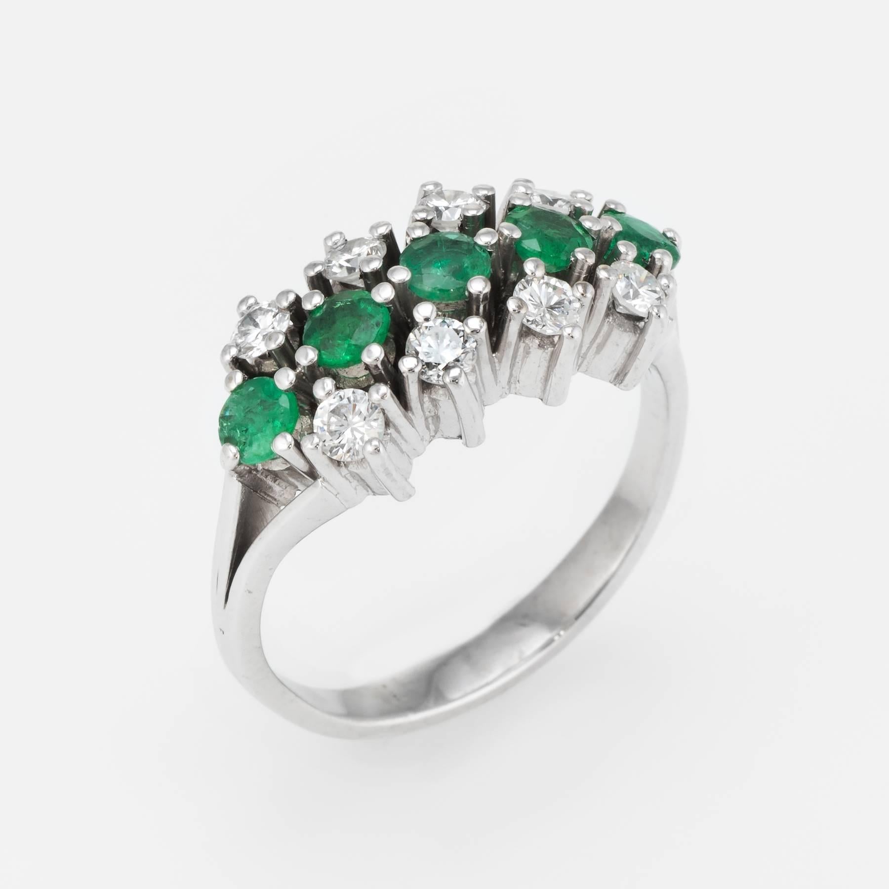 Elegant vintage anniversary band (circa 1950s to 1960s), crafted in 14 karat white gold. 

Centrally mounted faceted round cut emeralds are estimated at 0.10 carats each (0.50 carats total estimated weight), accented with 8 estimated 0.05 carat