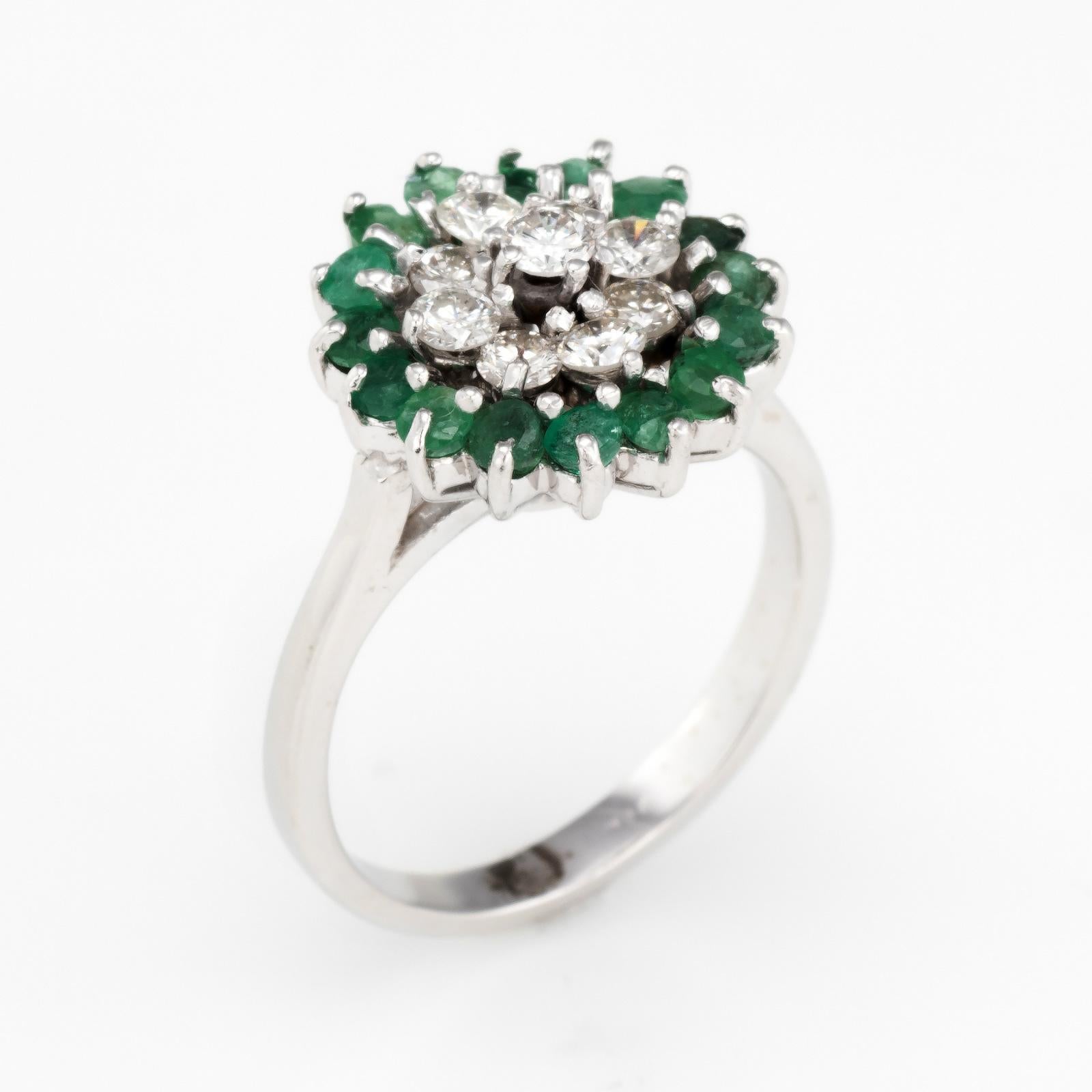 Elegant emerald & diamond cluster ring, crafted in 14 karat white gold (circa 1980s). 

Emeralds total an estimated 0.80 carats, accented with an estimated 0.42 carats of diamonds (estimated at H-I color and VS2-SI2 clarity).

The cluster design