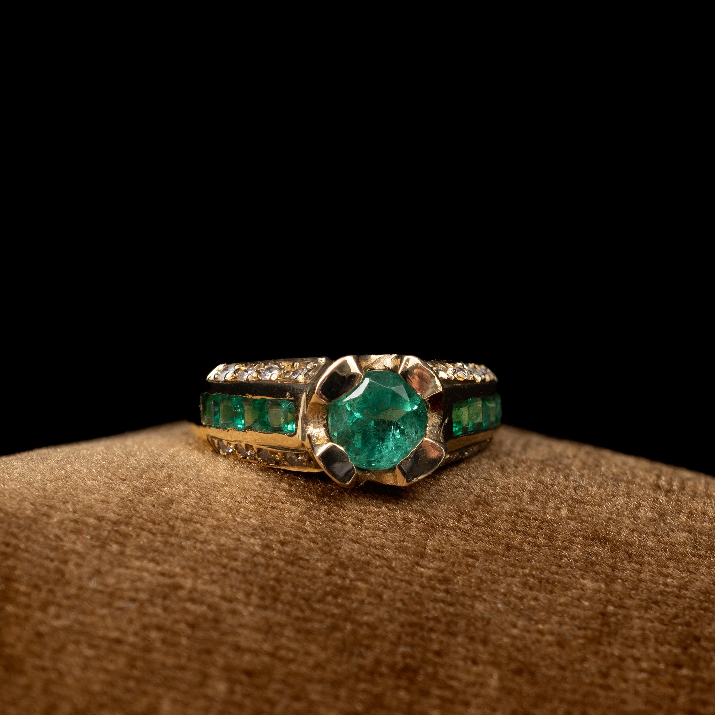 An outstanding Emerald and Diamond cocktail ring in 18 karat gold. 

The striking ring features 0.65 carat round cut natural emerald.
Shoulders set with a total of 8 square cut emeralds and 16 round cut diamond accents.

Ring size:US size: 6 3/4 