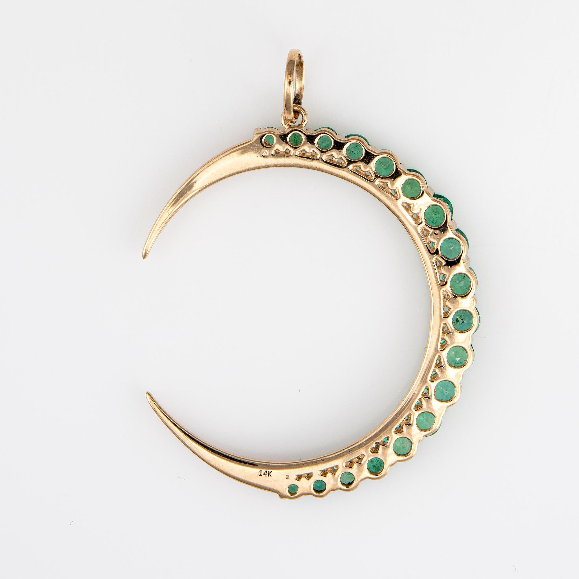 Finely detailed emerald & diamond crescent moon pendant crafted in 14 karat yellow gold. 

Diamonds total an estimated 0.39 carats (estimated at H-I color and VS2-SI2 clarity). The emeralds total an estimated 1.38 carats. The emeralds are in very