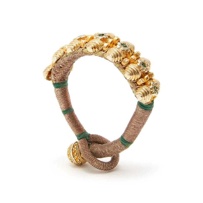 Based on a centuries old Rajasthani tribal design, this  stunning cuff bracelet is hand crafted by stitching emeralds and diamonds onto tightly woven gold silk thread.

- Natural faceted emeralds and brilliant cut diamonds.
- Set in 22 Karat gold