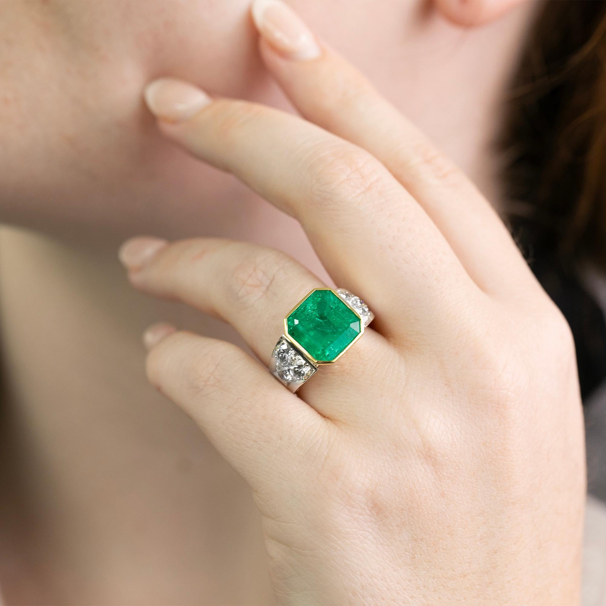 A beautifully hand-made cocktail dress ring. Crafted in two tones of gold featuring a central bezel set natural octagonal square cut emerald with the shoulders of the ring adorned with brilliant cut diamonds. The perfect statement piece to add to