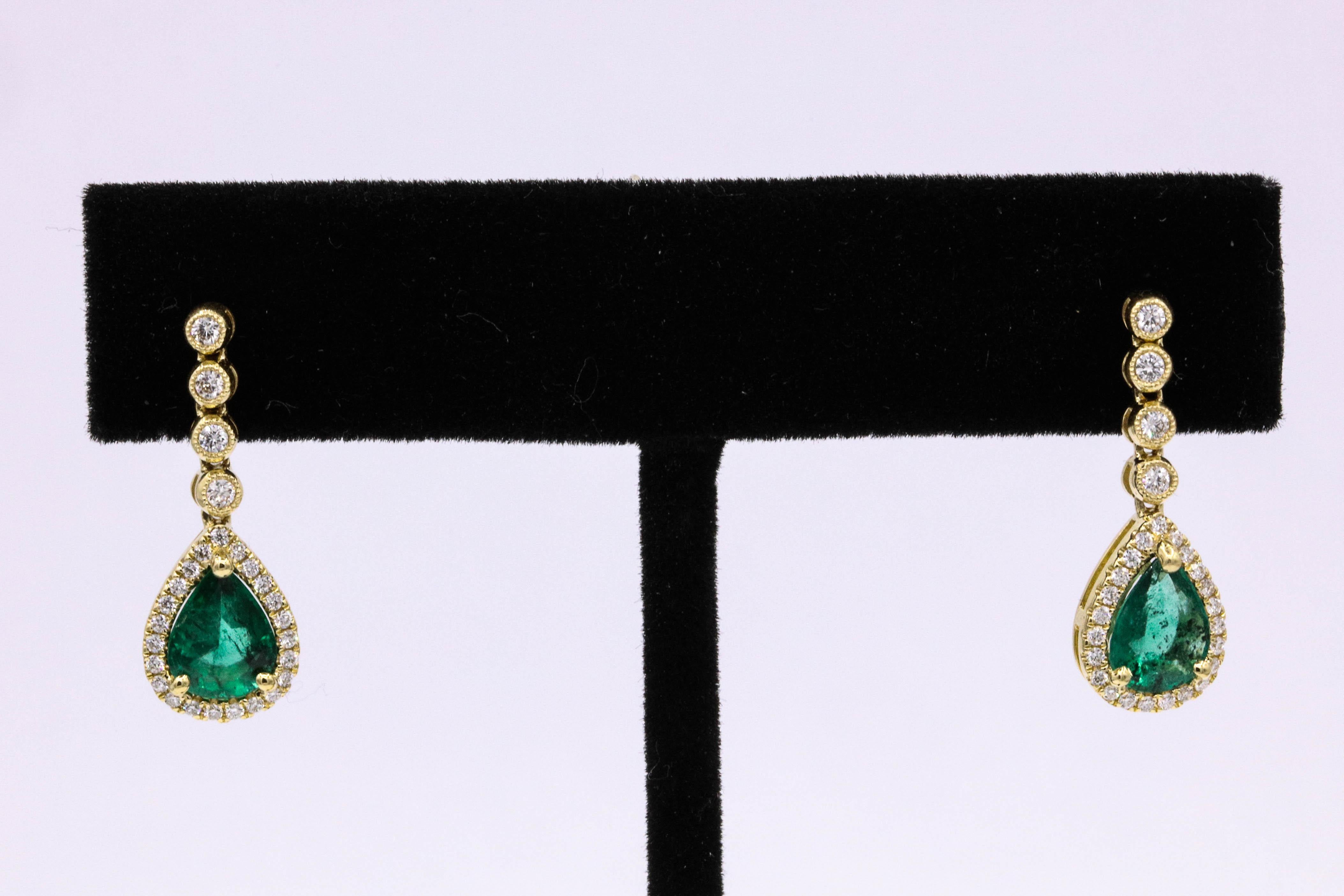 18K Yellow gold drop earrings featuring two pear shape Zambian emeralds, 1.60 carats, flanked with round brilliants weighing 0.35 carats.
Color G-H
Clarity SI