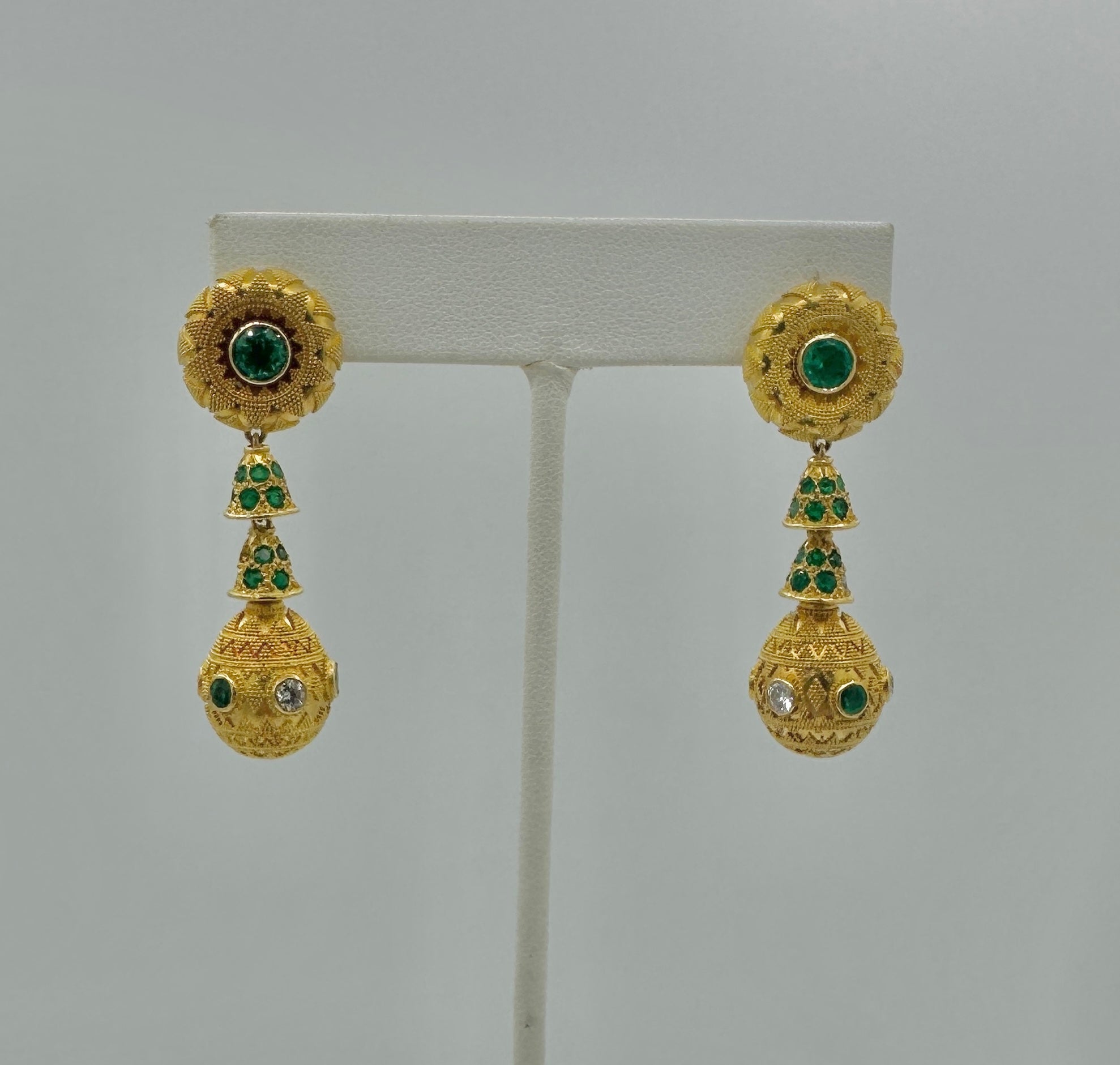 This is a spectacular pair of Emerald and Diamond Etruscan Revival Pendant Dangle Drop Earrings in 22 Karat Yellow Gold.   The  impressive earrings are 1 7/8 inches in length and have four articulated drop sections.  The tops are set with gorgeous