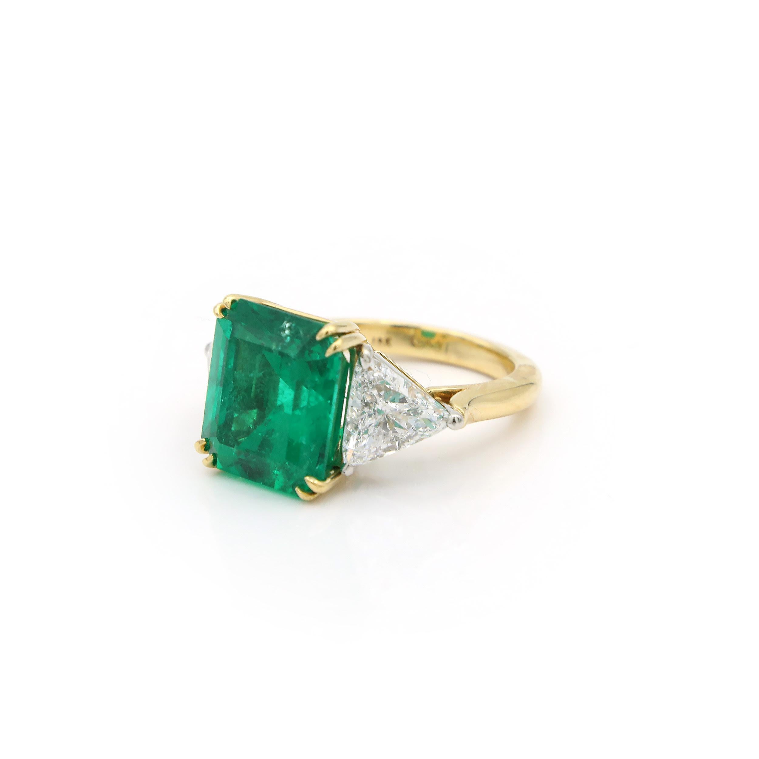 This is a stunning, exceptional piece, photographs don't give it justice!
It's an amazing 7.76 CT Emerald, Basket set and flanked by 2 trilliant cut diamonds. The emerald is vivid and transparent with inclusions. 
A truly romantic ring that warms
