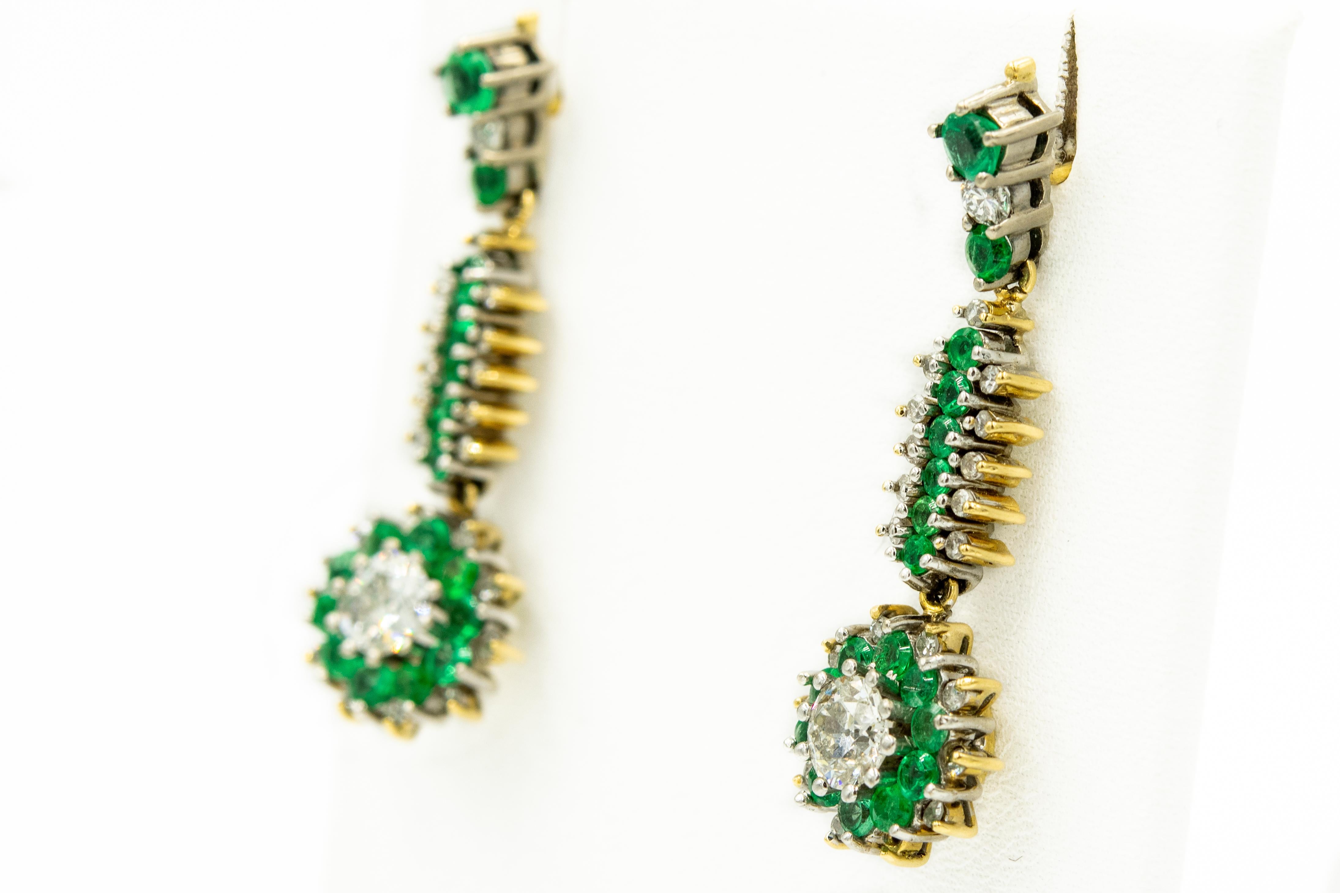 Custom made emerald and diamond earrings featuring a prong set 3 stone emerald and diamond top section leading to another section with emerald center with diamonds on the sides terminating at a pair of .55 carat European cut diamonds set in an