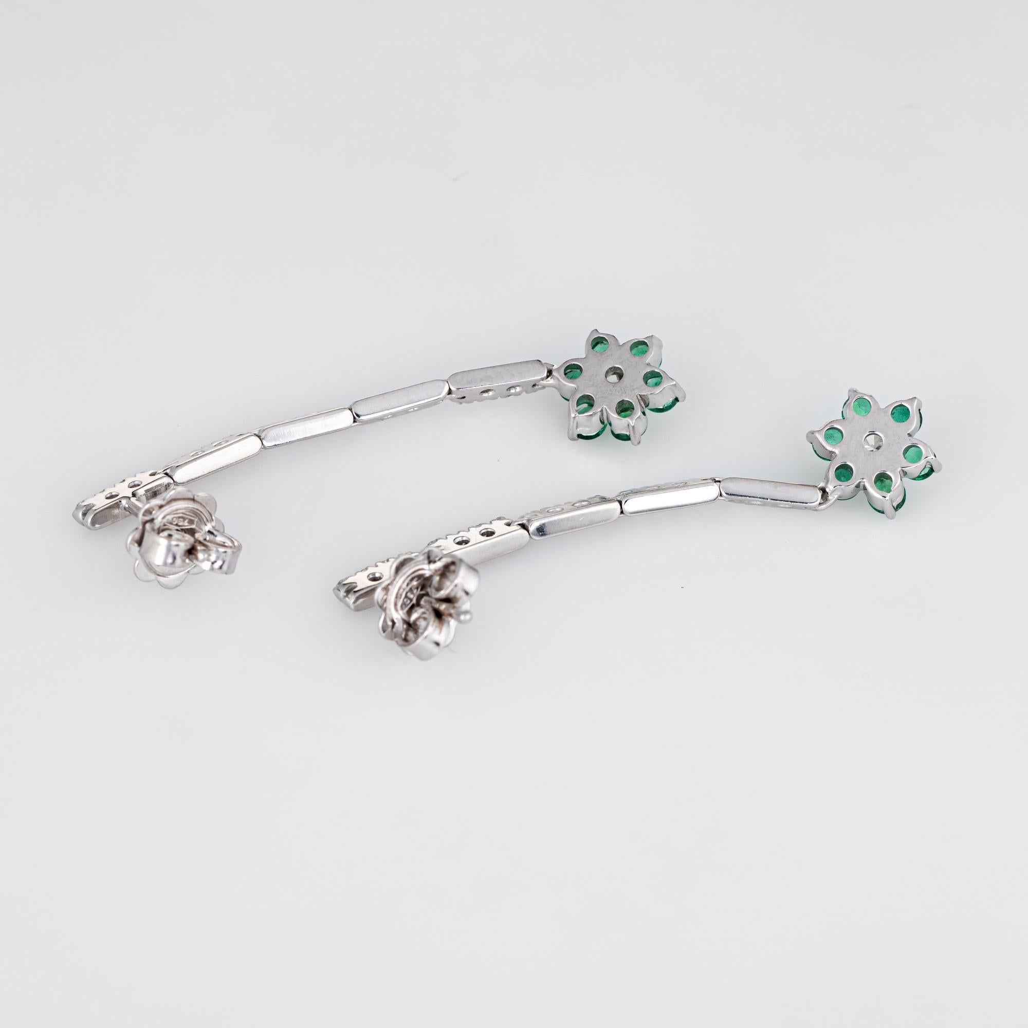 Elegant pair of emerald & diamond flower drop earrings crafted in 18k white gold. 

Faceted round cut Emeralds total an estimated 0.60 carats. The diamonds total an estimated 0.60 carats (estimated at G-H color and VS2 clarity). The emeralds are in