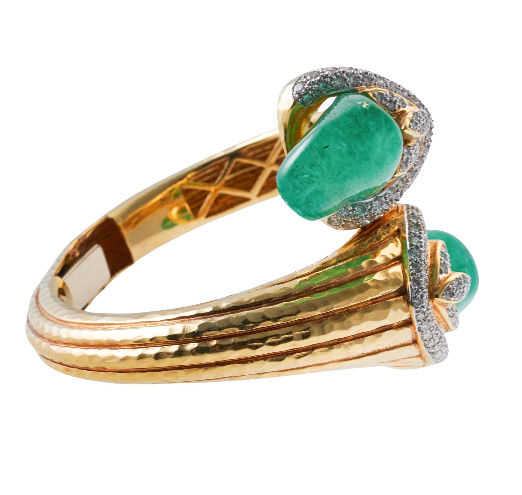 Impressive 18k gold bypass bangle bracelet, set with two polished emerald cabochons on each end, measuring approx. 23mm x 15mm, surrounded with approx. 0.60ctw H/SI diamonds. The bracelet will fit an approx. 7