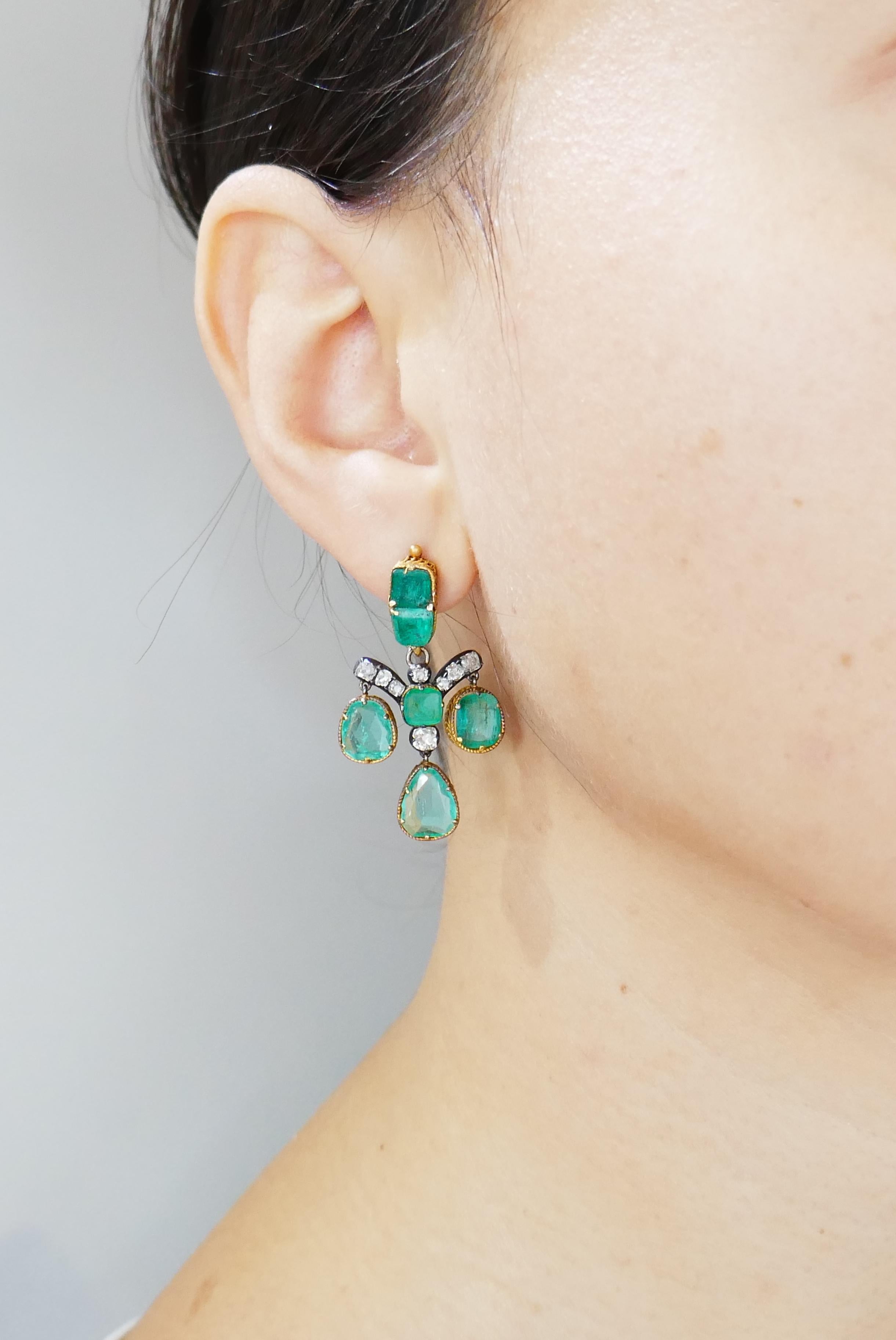 Dramatic yet wearable dangle earrings.
The earrings are made of 14 karat (tested) yellow gold and set with emeralds and old mine cut diamonds. Aged patina on gold accentuates antiquity of the earrings, vivid green color of the emeralds keeps an eye
