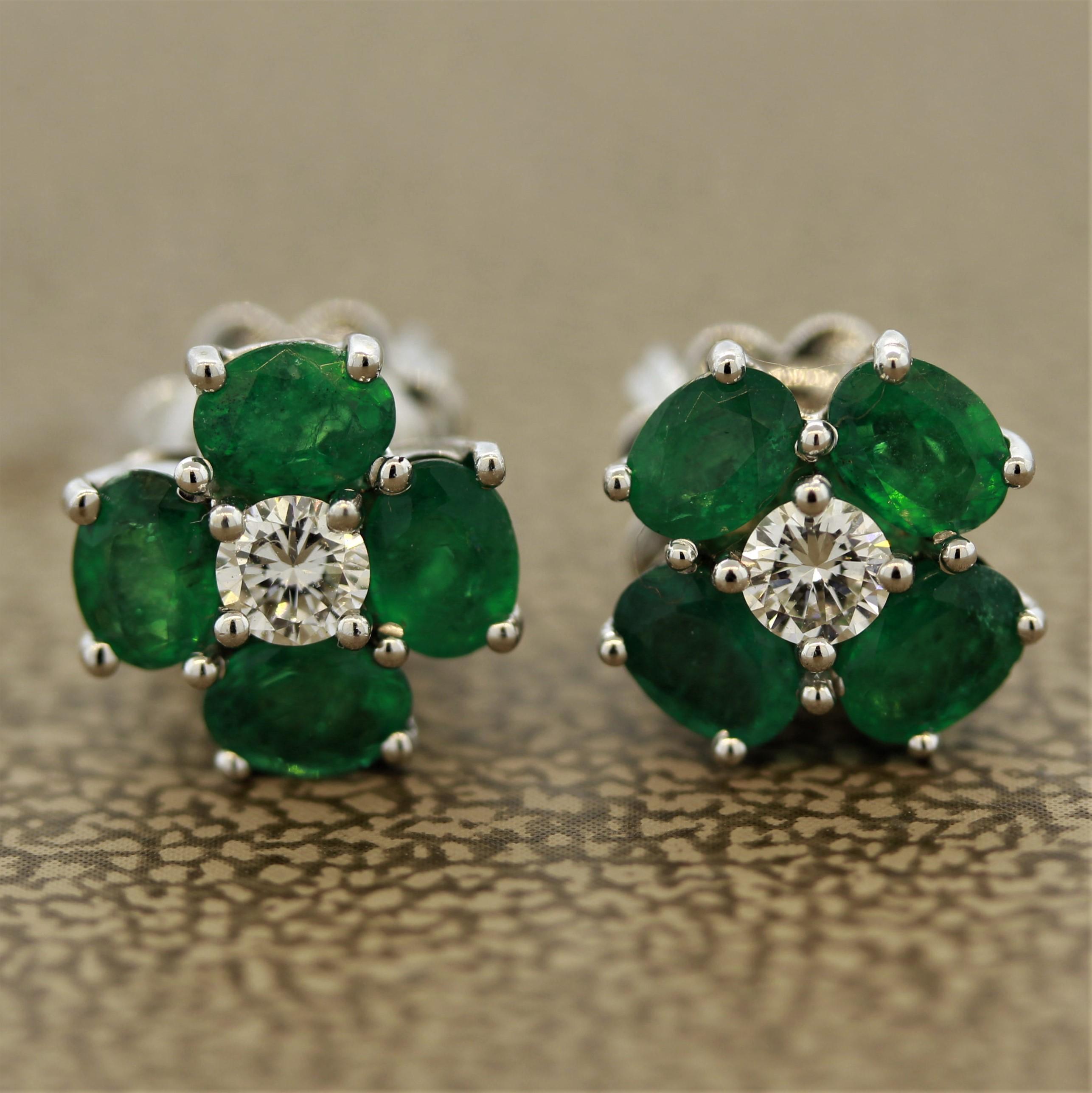 A lovely pair of earrings featuring fine emeralds with a bright and vivid green color. They are accented by a round brilliant cut diamond in the center and the gems weigh a total of 1.50 carats. 

Made in 18k white gold.