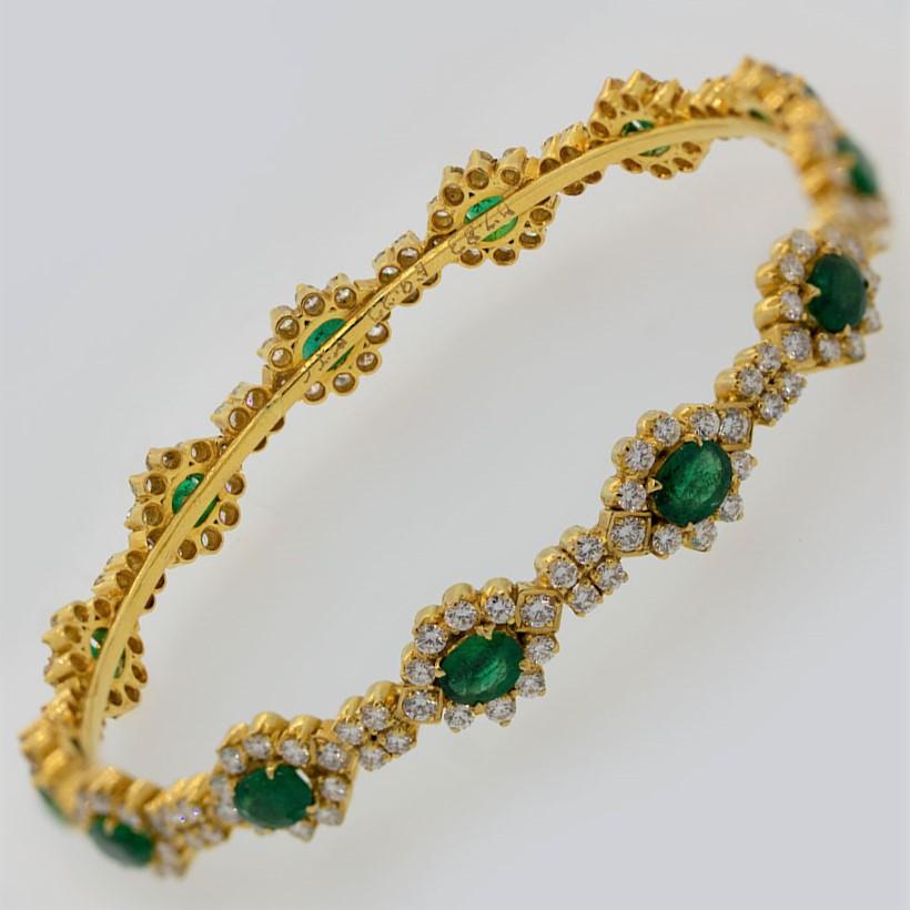 A stylish bangle bracelet featuring oval shaped emeralds weighing a total of 4 carats. They are accented by 5.00 carats of round brilliant cut diamonds set in a lovely pattern around the entirety of the bangle. Made in 22k yellow gold and ready to