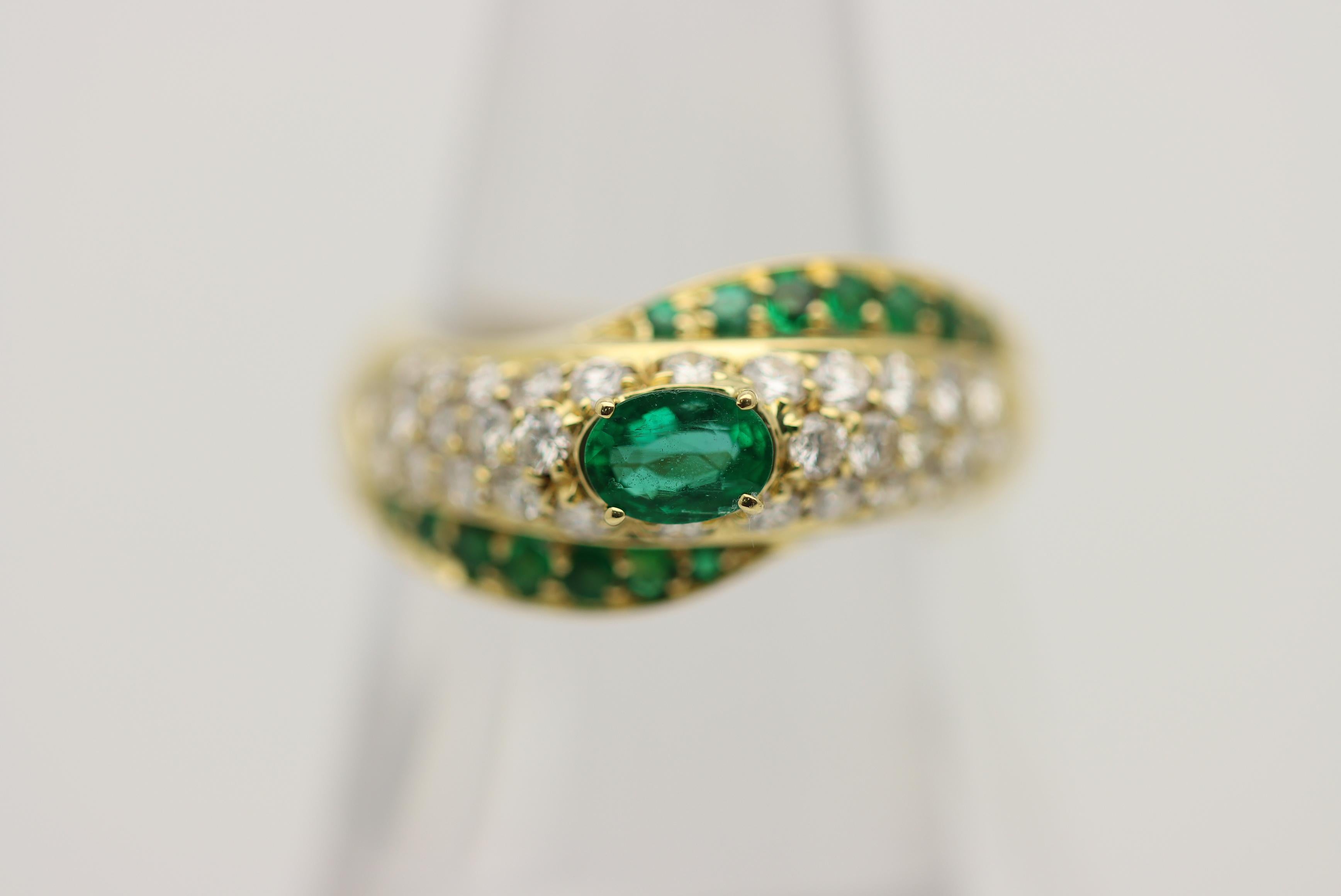 A sleek and stylish ring made in 18k yellow gold. It features 0.85 carats of bright green emeralds including the large oval-shape emerald in the center of the ring. It is complemented by 0.96 carats of round brilliant-cut diamonds set in the center