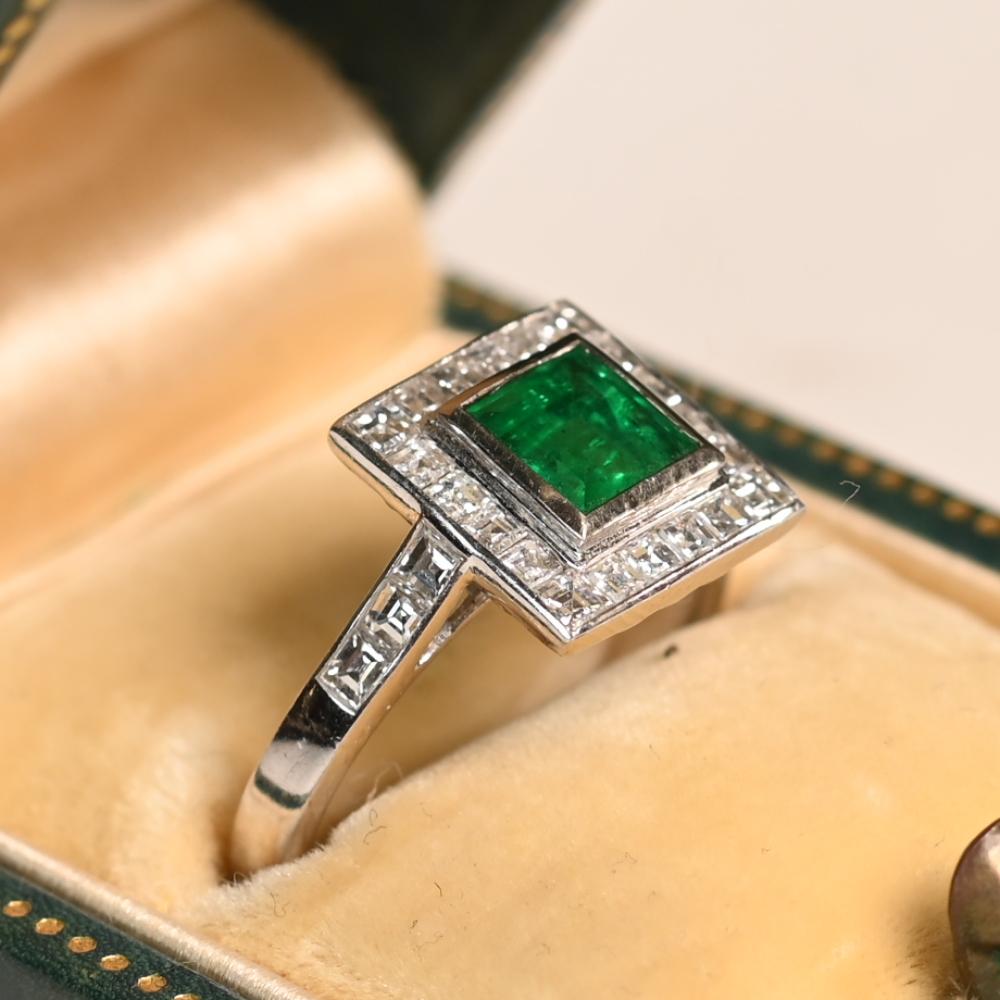 In der Mitte dieses exquisiten Rings befindet sich ein bezaubernder Smaragd im Smaragdschliff mit einem Gewicht von etwa 1 Karat. Der leuchtend grüne Edelstein ist sicher in 18-karätigem Gelbgold gefasst, was seine Brillanz und seine zeitlose