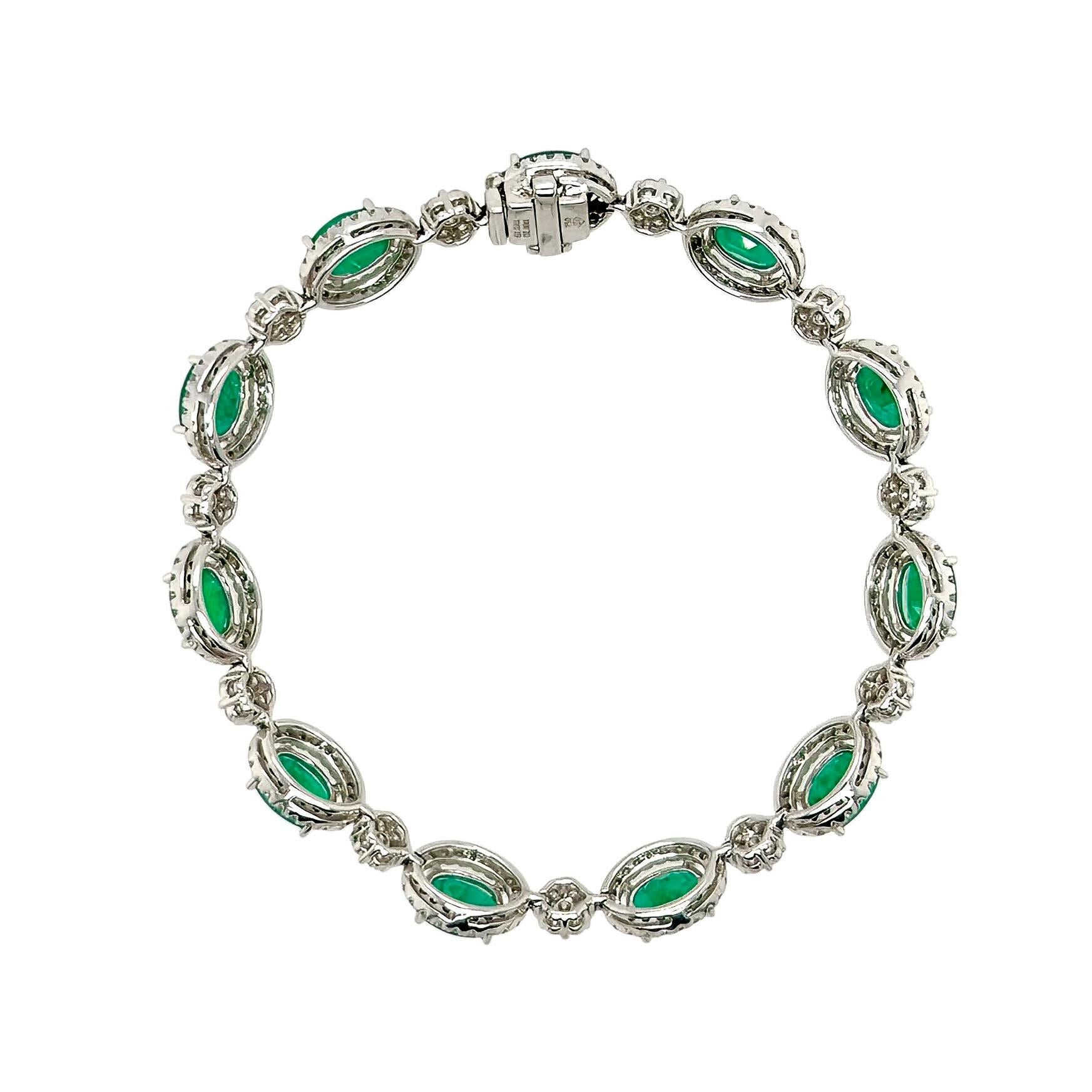 An 18 karat white gold, emerald and diamond bracelet.  Designed as 11 oval faceted emeralds surrounded by approximately 20 round brilliant cut diamonds each, alternating with 11 florets set with seven round brilliant cut diamonds each.  Total