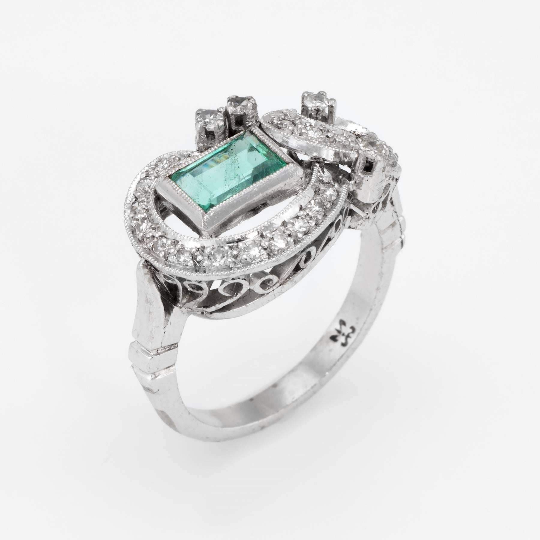 Elegant vintage cocktail ring (circa 1940s), crafted in palladium. 

Centrally mounted emerald cut emerald measures 6mm x 4mm (estimated at 0.50 carats), accented with an estimated 0.29 carats of single cut diamonds (estimated at I-J color and