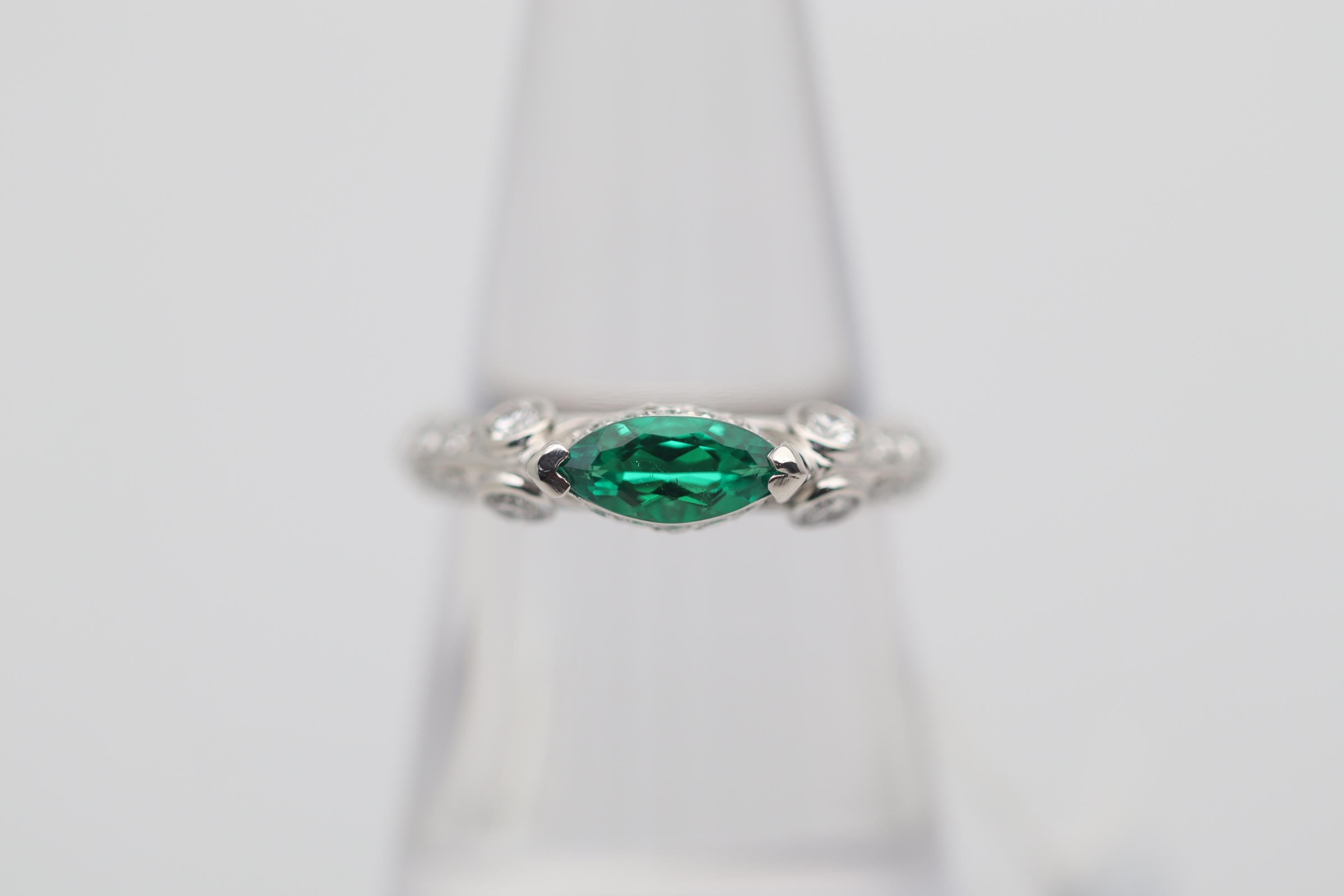 A sleek and sexy platinum ring featuring a 0.47 carat marquise shape emerald. It has a rich and fine vivid grass green color that pops. It is complemented by 0.56 carats of round brilliant-cut diamonds set around the ring adding brilliance and