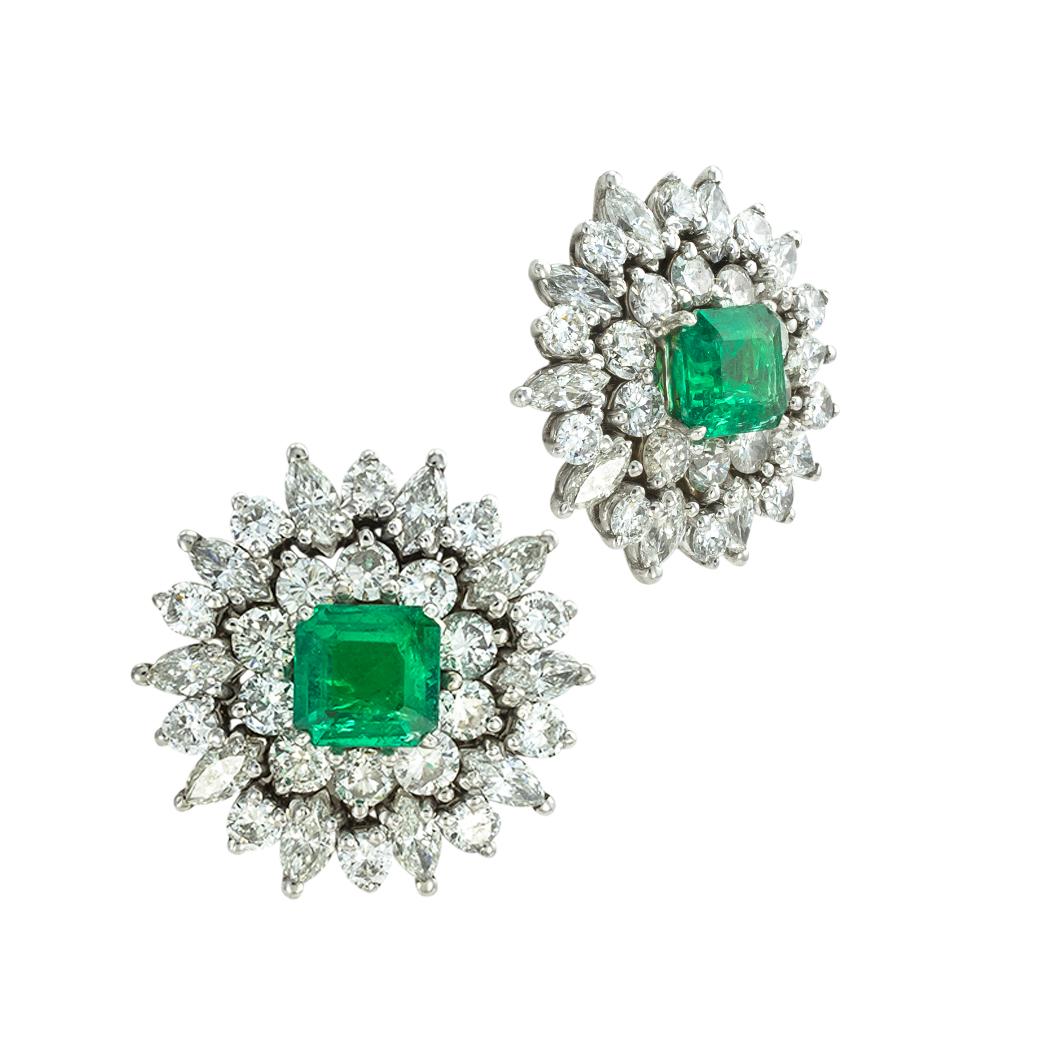 Emerald and diamond cluster earrings circa 1960. *

ABOUT THIS ITEM:  #E-DJ12C. Scroll down for specific details. These stunning emerald and diamond earrings feature a pair of green emeralds centering upon a radiating, double-step border set with
