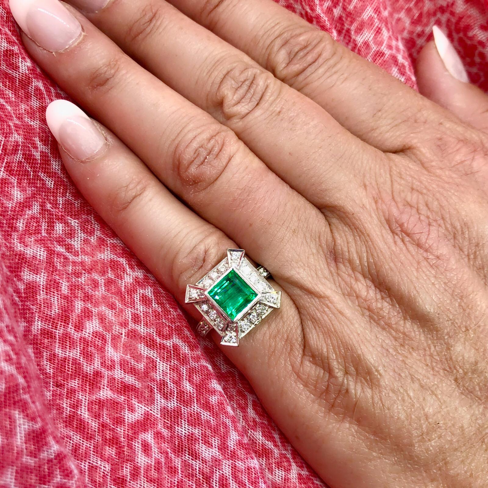 A contemporary Deco style ring featuring a square cut 2.25 carat emerald in a platinum setting enhanced with 30 round brilliant cut diamonds, totaling 0.82 carat. The ring measures 16mm to 2mm wide and is currently a size 4.75 with room to size up