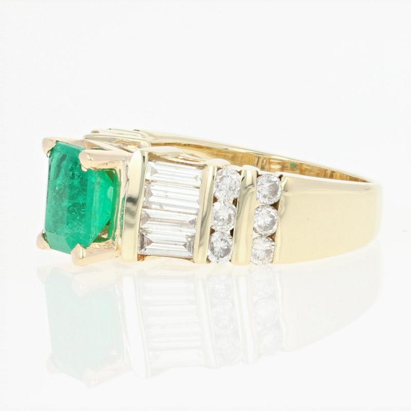 Slip on this gorgeous ring for a brilliant splash of color! Fashioned in 14k yellow gold, this vivacious piece showcases a lively emerald solitaire beautifully accompanied by shimmering baguette and round brilliant cut diamonds which grace the