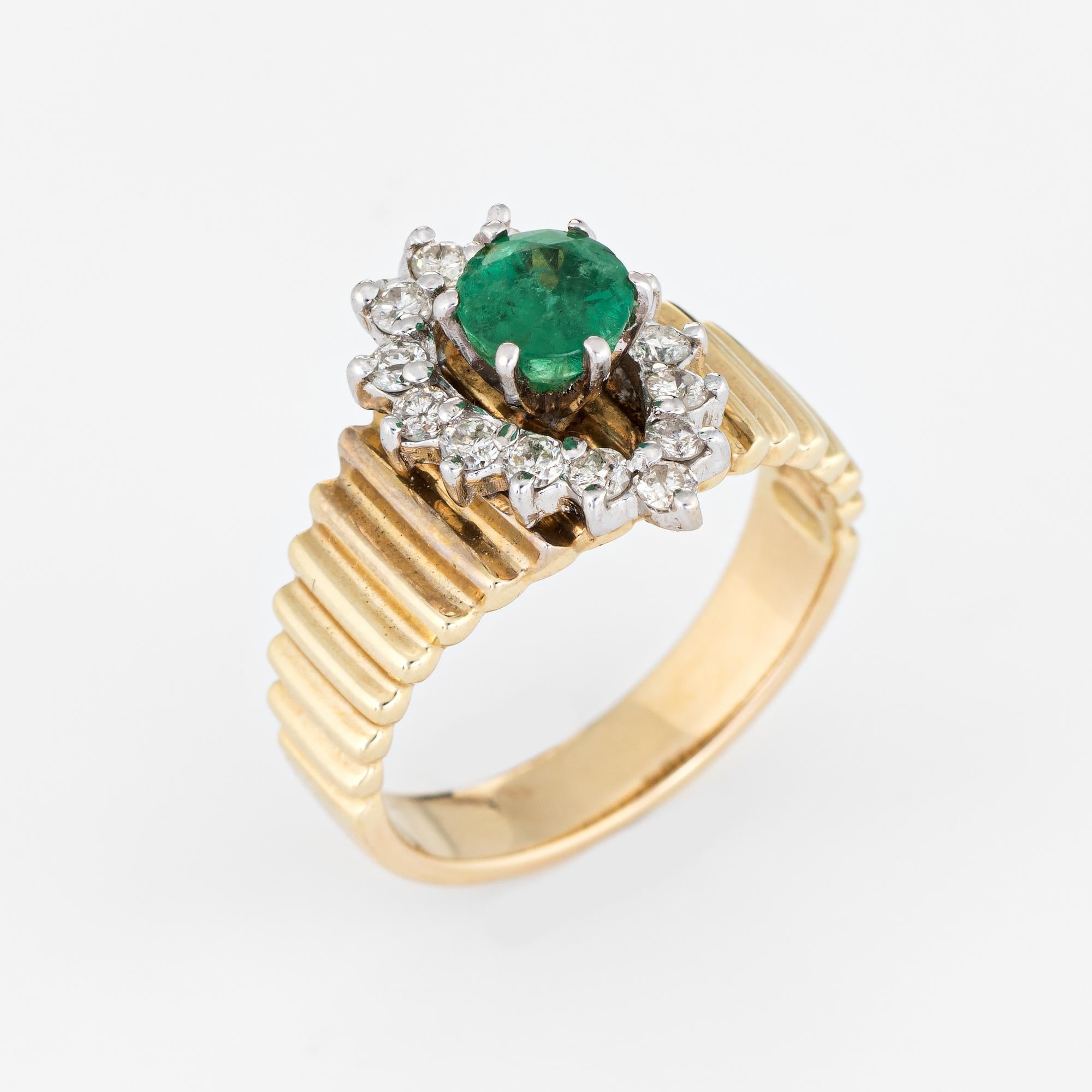 Stylish vintage emerald & diamond ring (circa 1970s) crafted in 14 karat yellow gold. 

Round faceted emerald measures 5.5mm (estimated at 0.62 carats), accented with 14 estimated 0.03 carat round brilliant cut diamonds. The total diamond weight is