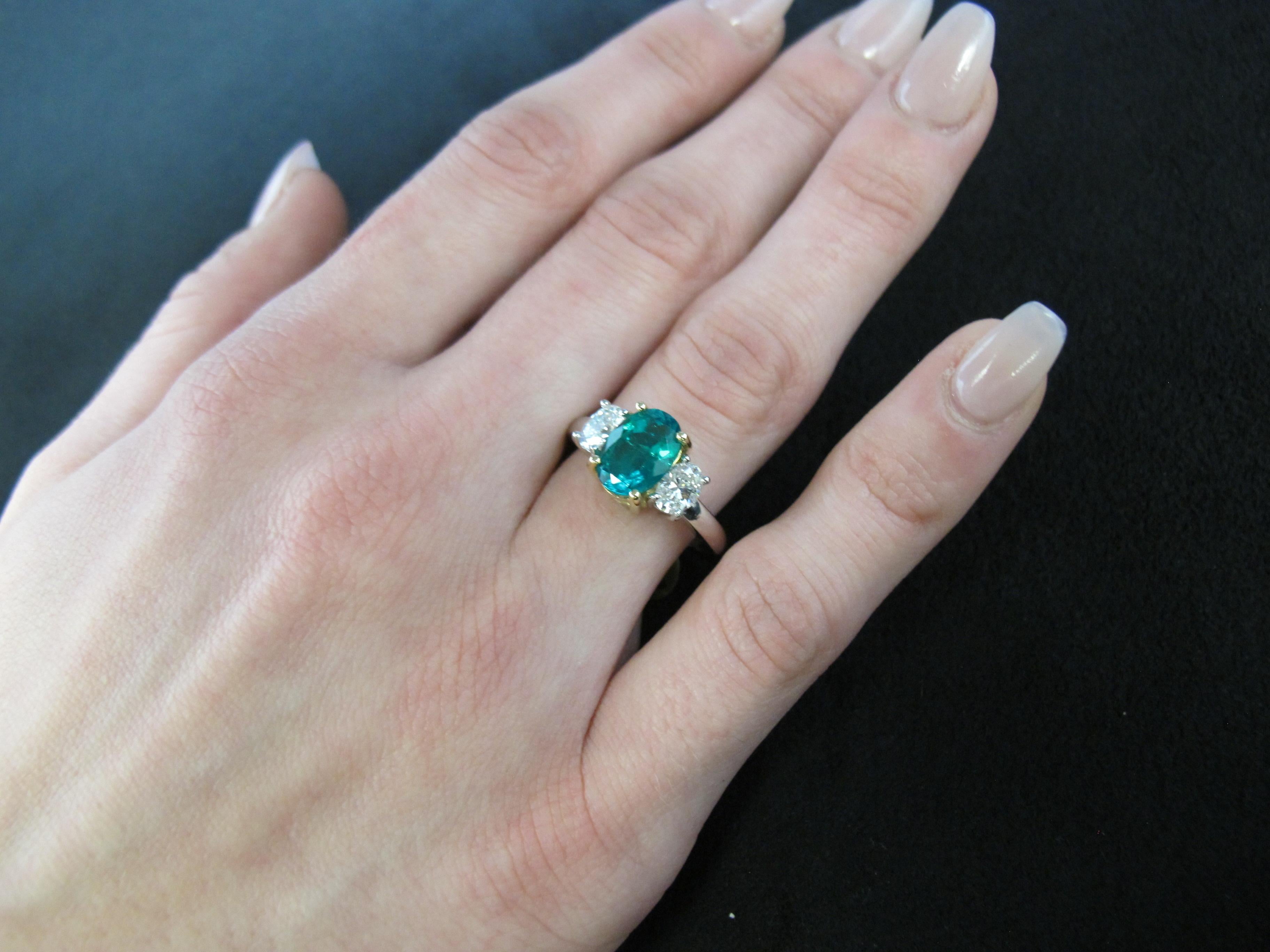 This is a classically elegant 3-stone ring. It features a rich, emerald-green emerald that is accompanied by  a Gemological Institute of America certificate that states it's origin as Colombian.  The emerald weighs 1.75 carats and  measures 