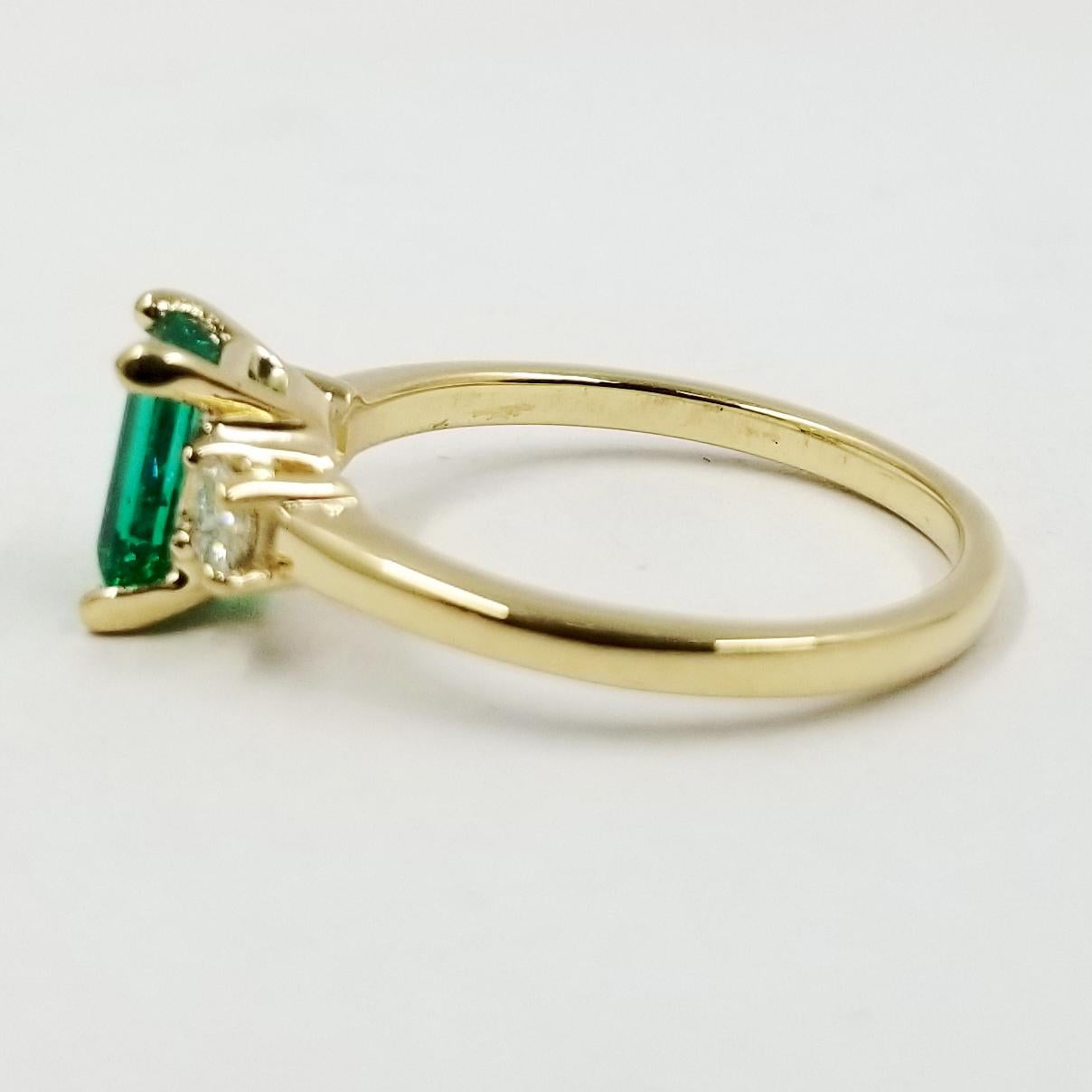 New 14 karat yellow gold ring featuring one 0.85 carat Emerald cut emerald and 2 Princess cut diamonds totaling 0.20 carat of VS clarity & G color. Current finger size is 7.5; purchase includes one free sizing.