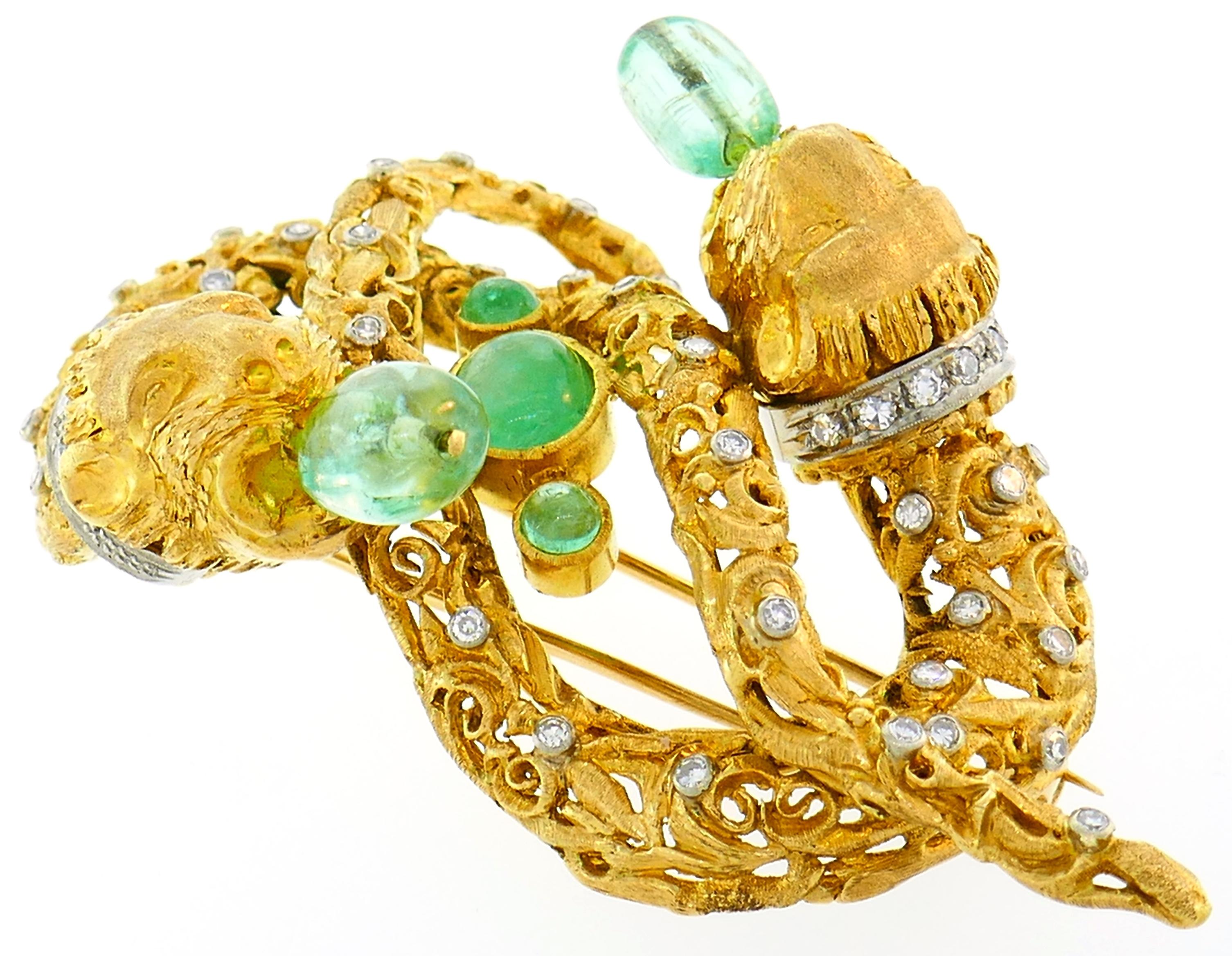 Popular Chimera Heads clip created in the 1970's. Ornate and made with great attention to details, it is definitely a conversational piece. 
It is made of 18 karat yellow gold, set with single cut diamonds and five emerald cabochons. The diamonds