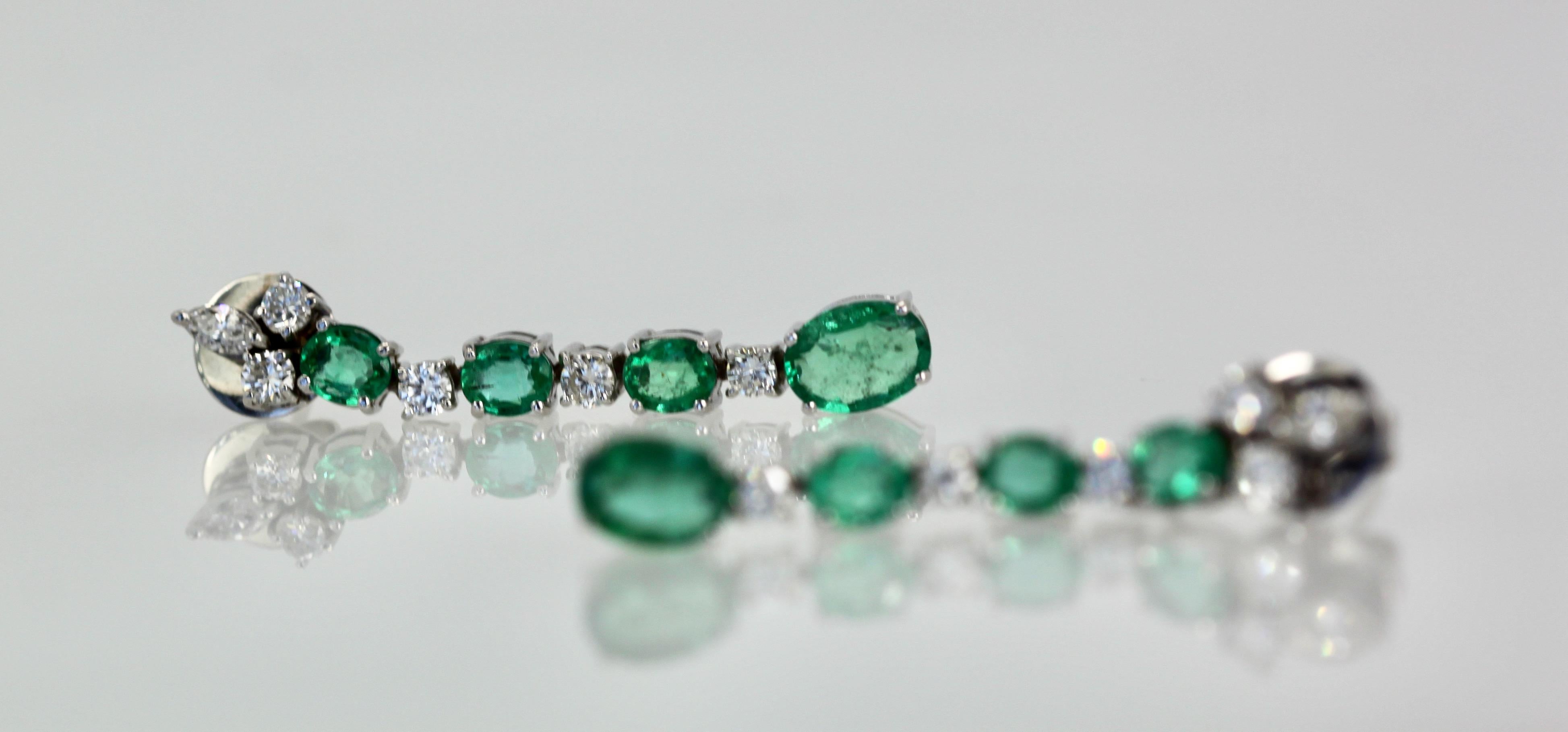 These lovely Emerald Drop Earrings are done in 18K White Gold and is set with 4 Emeralds each, 6 Diamonds of 0.15 points each, 3 Emeralds of approximately 1/2 Carat each and the bottom Emerald 1 carat each. TCW is 5 carats. The length of these