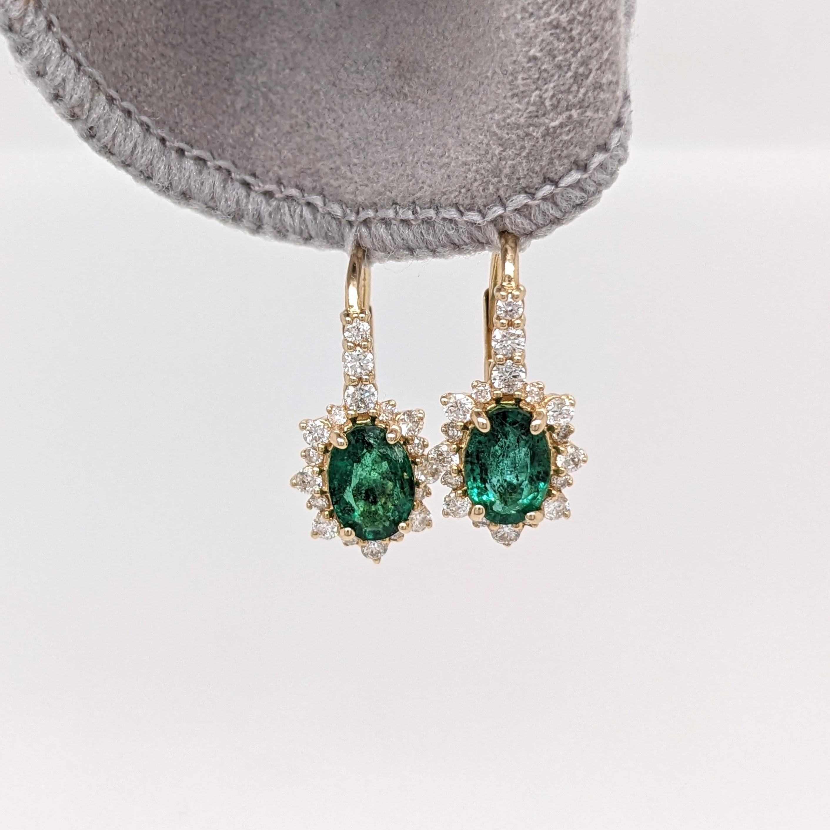 These beautiful pair of drop earrings feature 2.25 carat weight oval emerald gemstones with a halo of natural earth mined diamonds and a diamond studded bail, all set in solid 14K gold. These earrings can be a beautiful birthstone gift for your