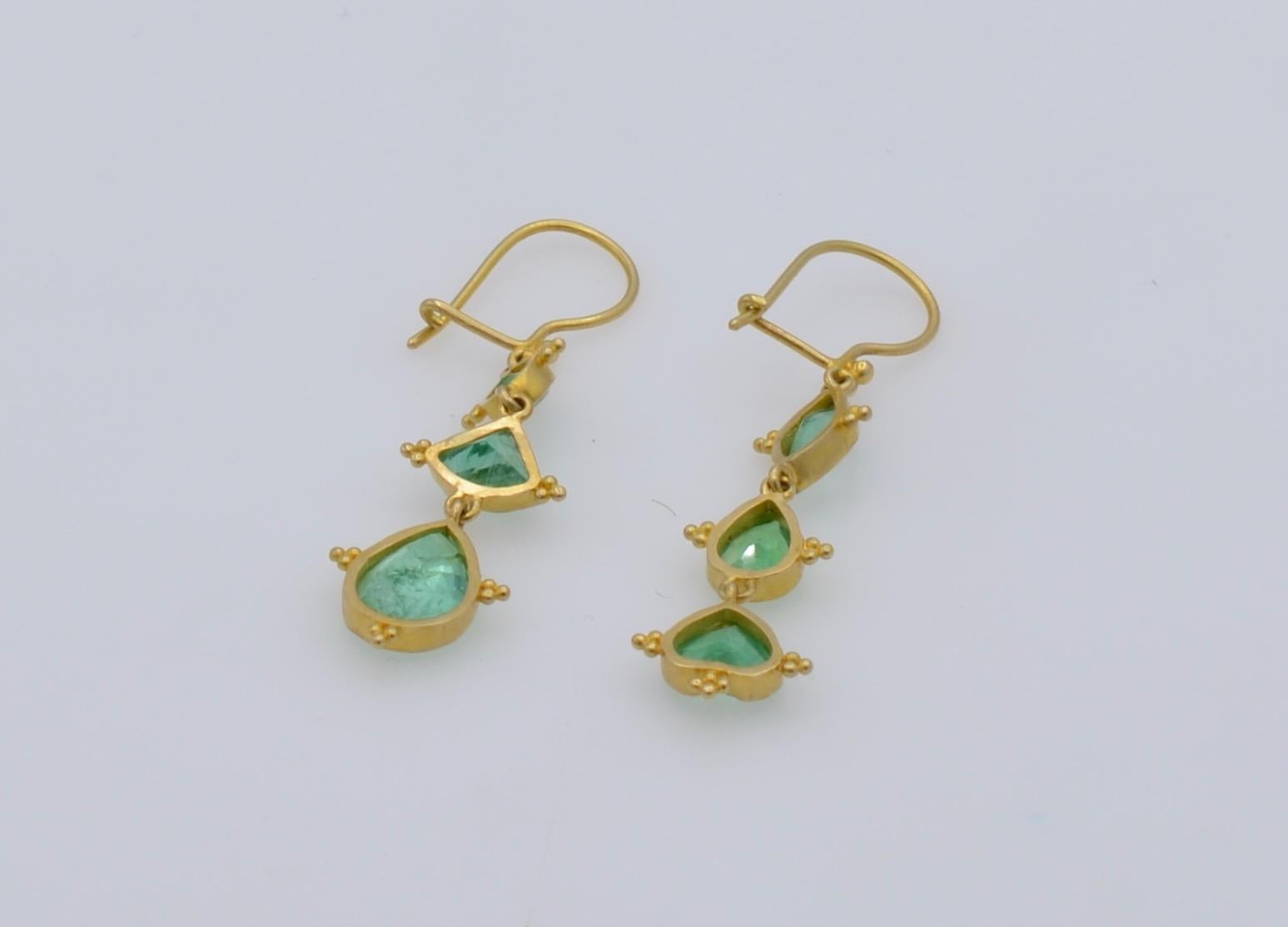 These artistic Steven Battelle designed asymmetrical emerald earrings hang in groups of three with marquise, pears, hearts and triangles set in 18K Yellow gold. The exquisite design and attention to detail create a beautiful one of a kind contrast