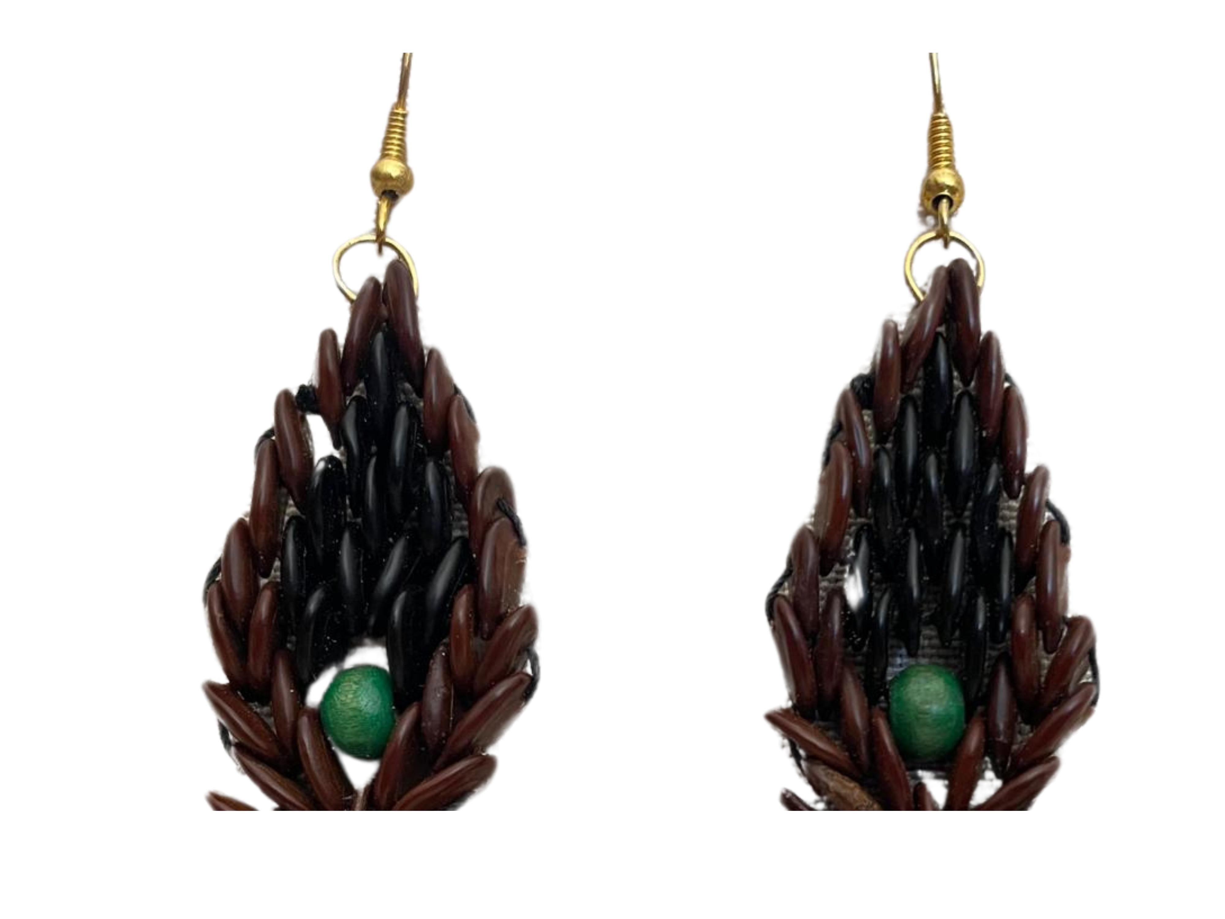 Voici les boucles d'oreilles Botanique Emerald Flame - un chef-d'œuvre de l'art de la table méticuleusement fabriqué à la main à partir de graines de tamarin sauvage. Cette boucle d'oreille faite à la main avec une perle de bois verte au centre