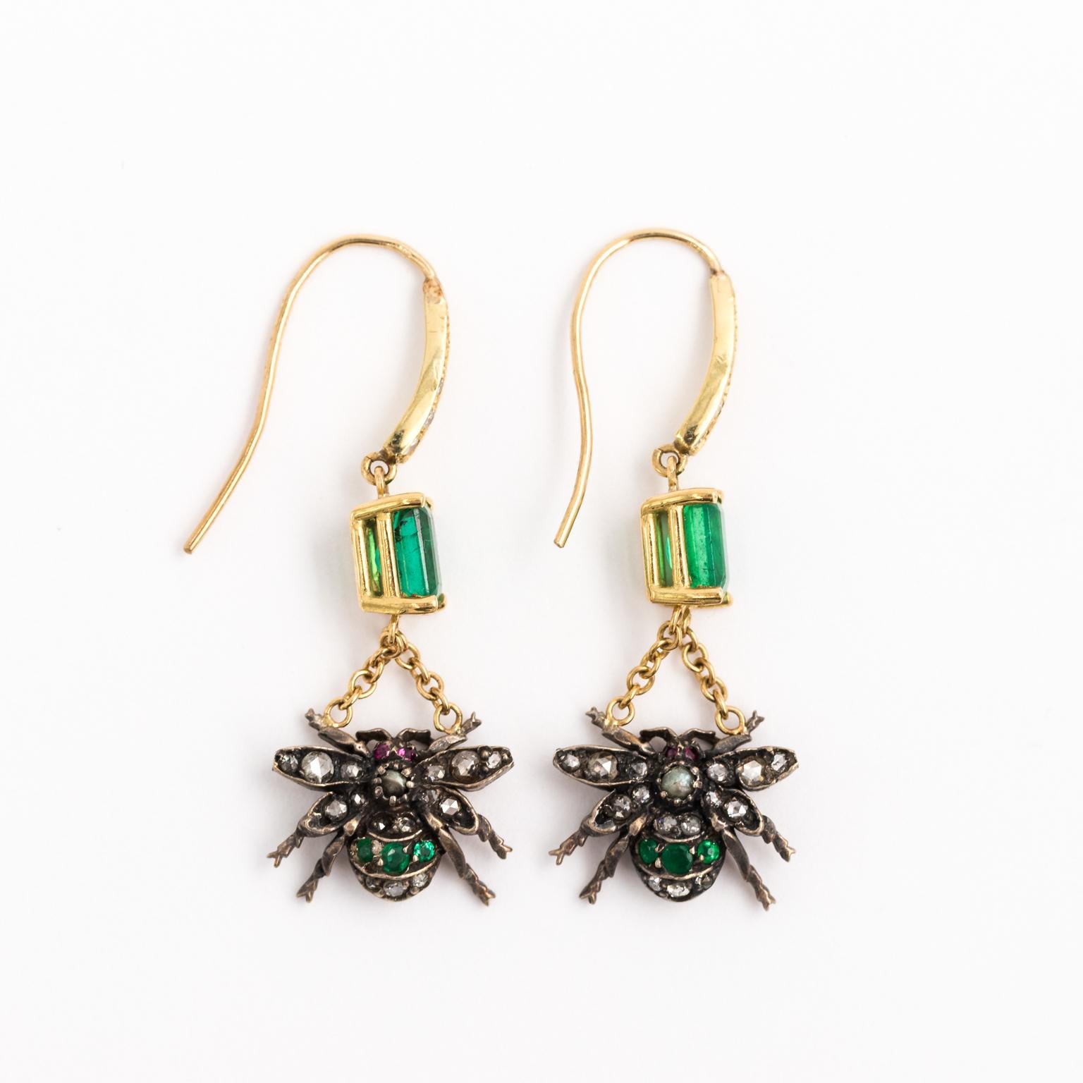 18 Karat Yellow Gold and Sterling Silver fly shaped earrings with 1.40 carat Emerald cut Columbian emeralds with rose cut Diamond, Ruby, and seed Pearl.
