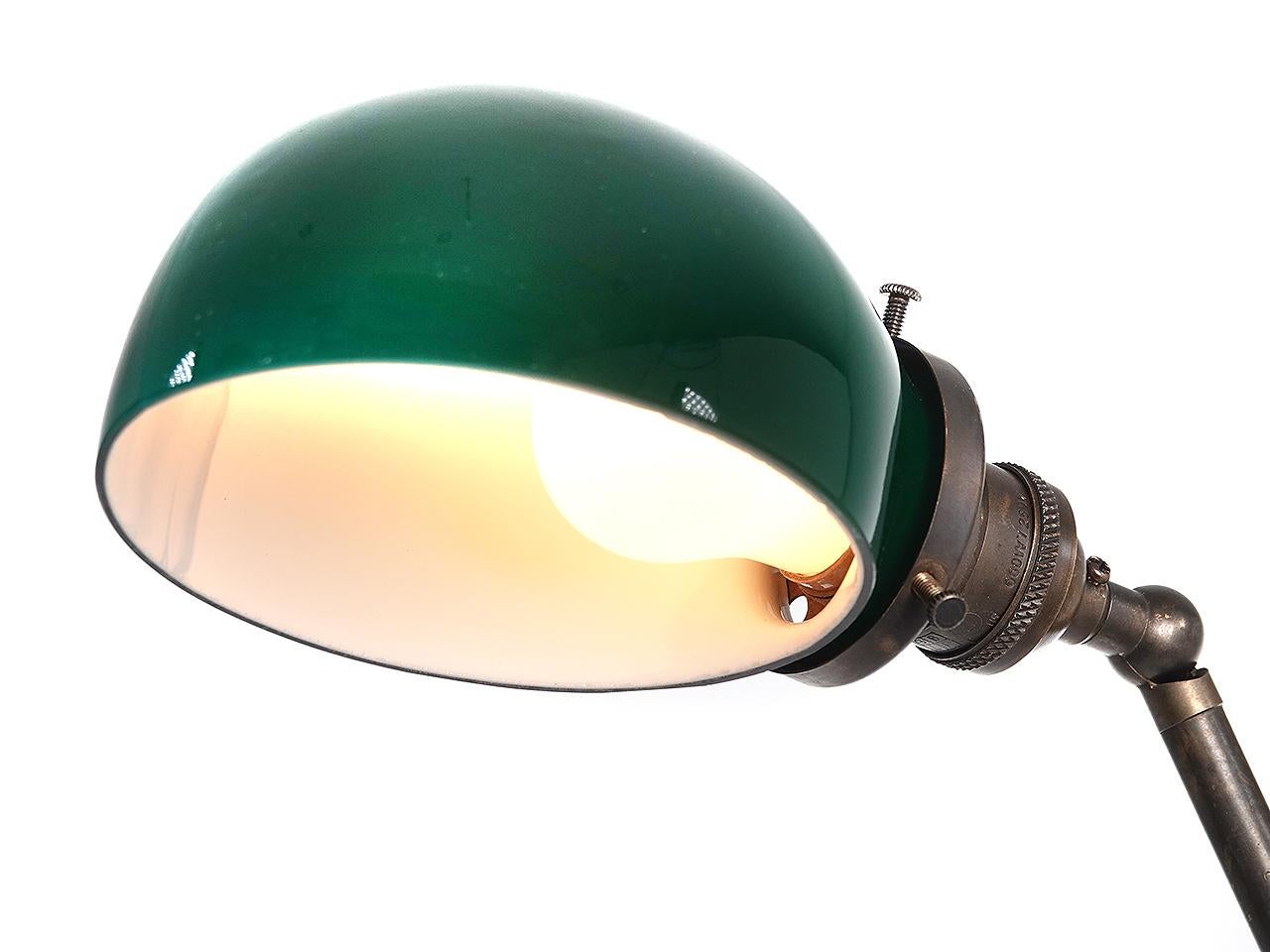 This is a desk lamp with a very simple and elegant look. It features a small emerald over white sandwich glass shade. The base has a lure shaped bracket that lets the ball counter weight pass through.