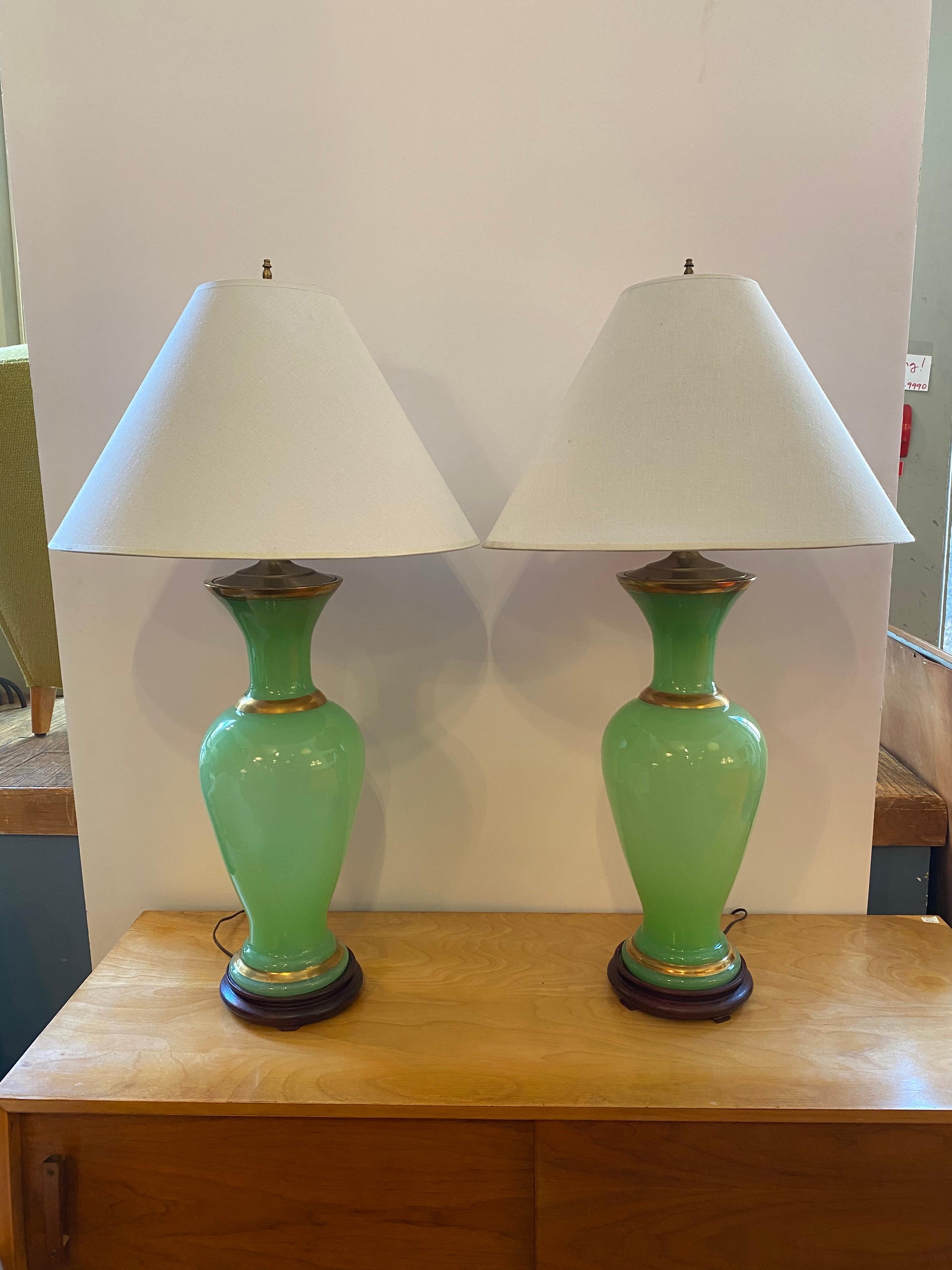 Emerald blown glass table lamps. Beautiful color that glows when the lamp is turned on! Gold accent bands add to the design. Lamps sit on small wood bases. Recently rewired and ready to go! Green glass bodies measure 22