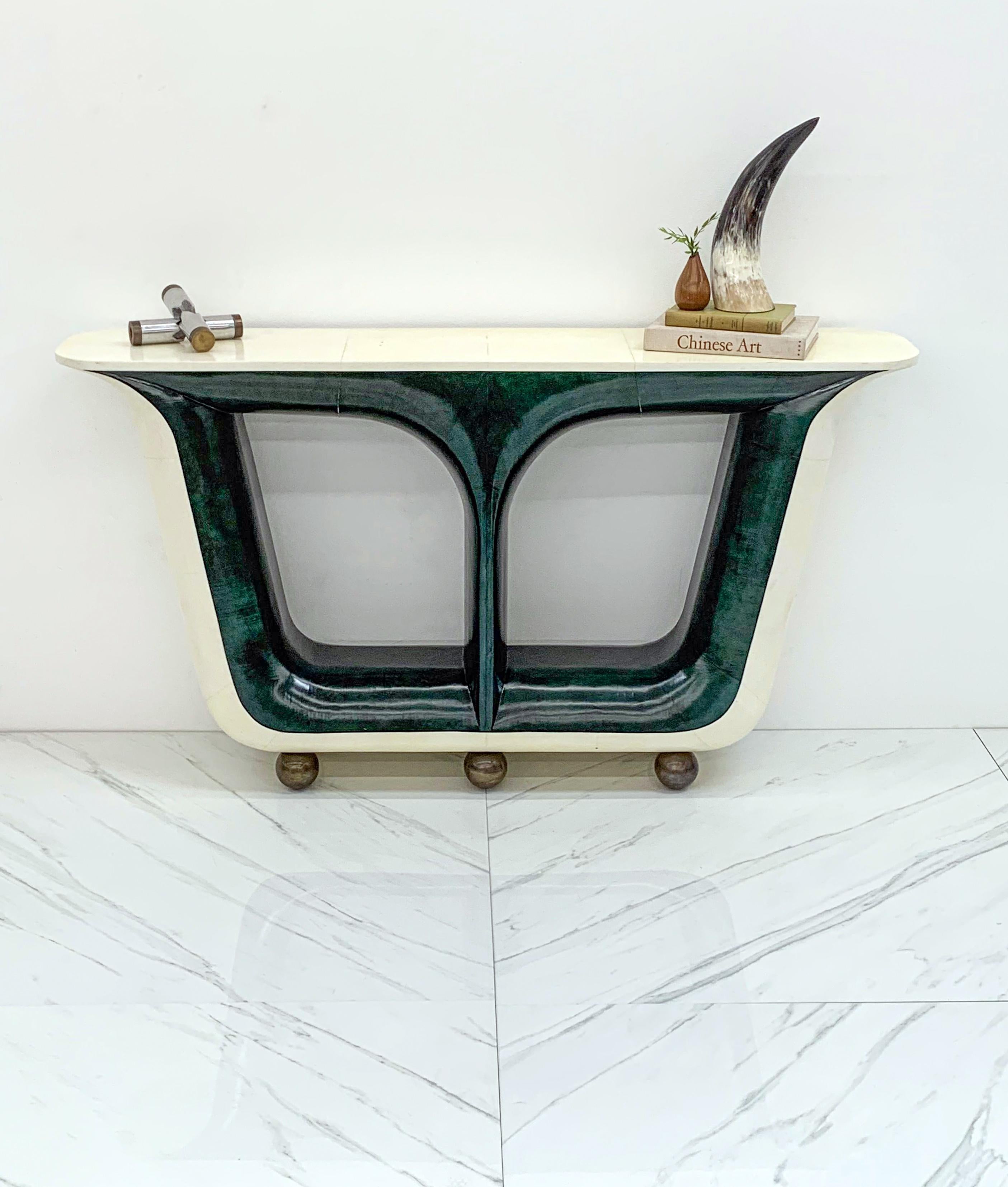 This console table is absolutely stunning. With emerald / malachite green lacquered goatskin and cream parchment, and bronze sphere legs this piece embodies high style deco luxury. This piece appears to have a makers mark branded / burnished onto