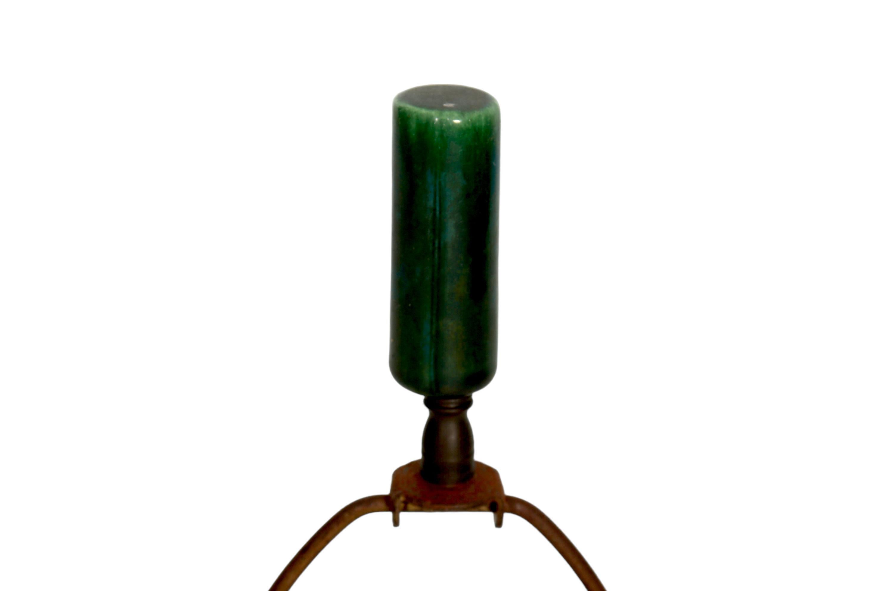An emerald green, atomic style ceramic table lamp. Shaped like a cactus, with a reeded vase and a decorative band around the base pressed to give the look of emerald cut jewels. Stands on three black wrought iron legs with scrolled feet. On top is a