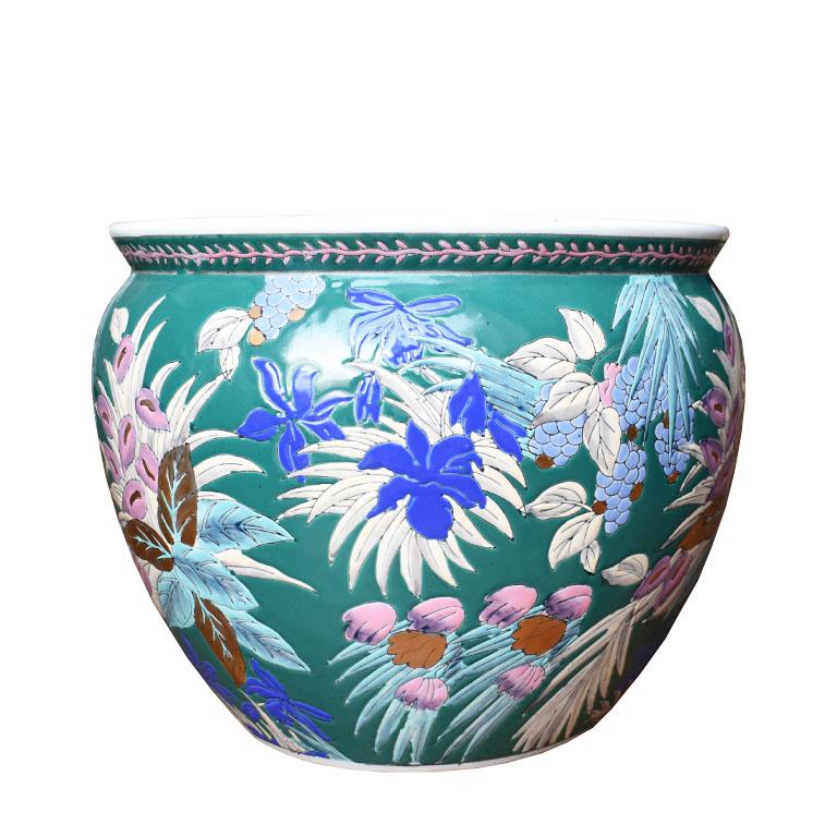 This colorful planter is a great way to add a pop of color to any patio. It features a verdant floral motif that surrounds the round base on an almost emerald dark green background. Scenes reminiscent of a jungle are of pink and green leafy flowers,