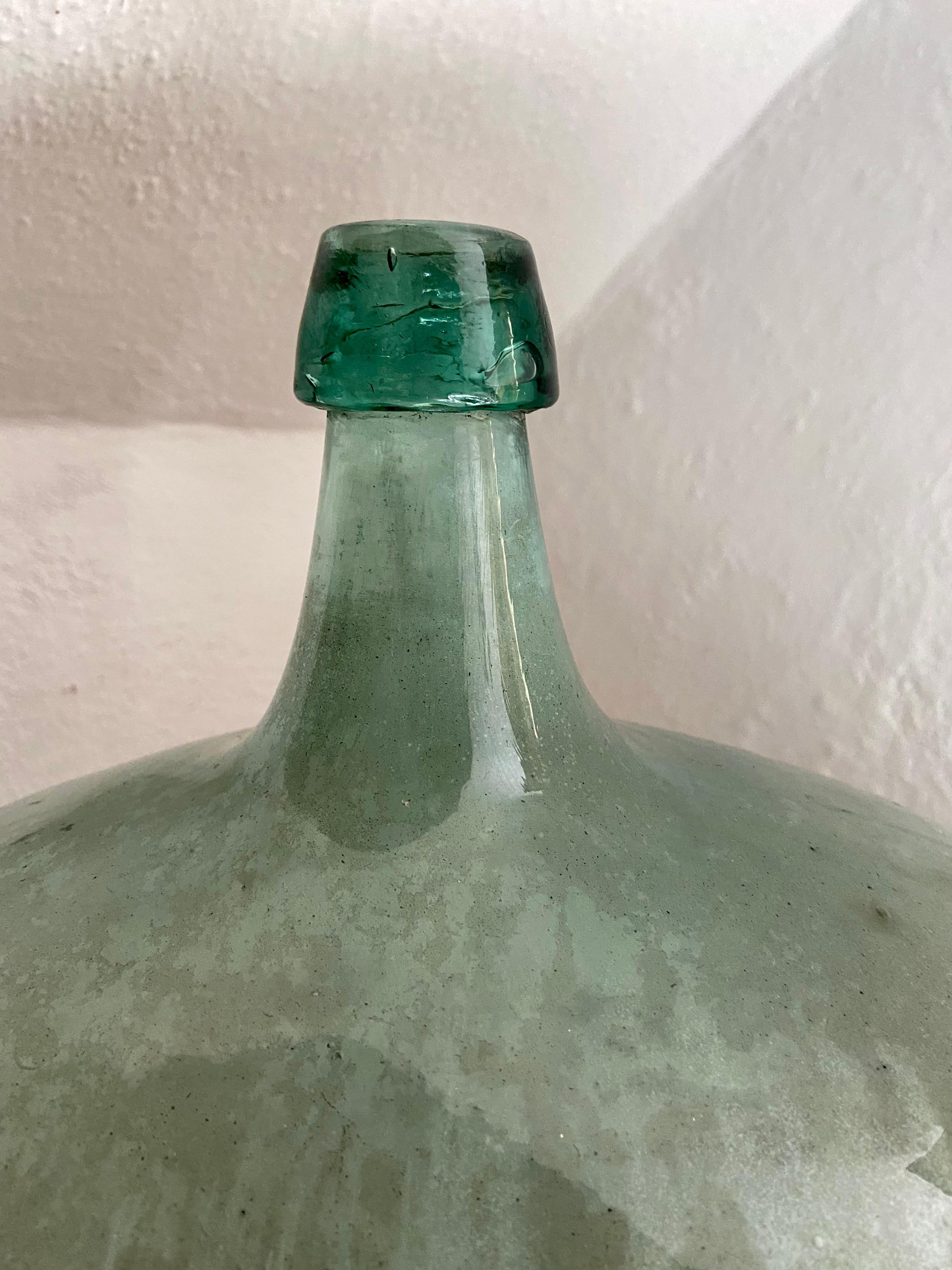 Hand-blown glass demijohn from Puebla, Mexico. These bottles were typically crafted in the early part of the 20th century. Light turquoise green and white coloration. Originally used to transport local wine.
