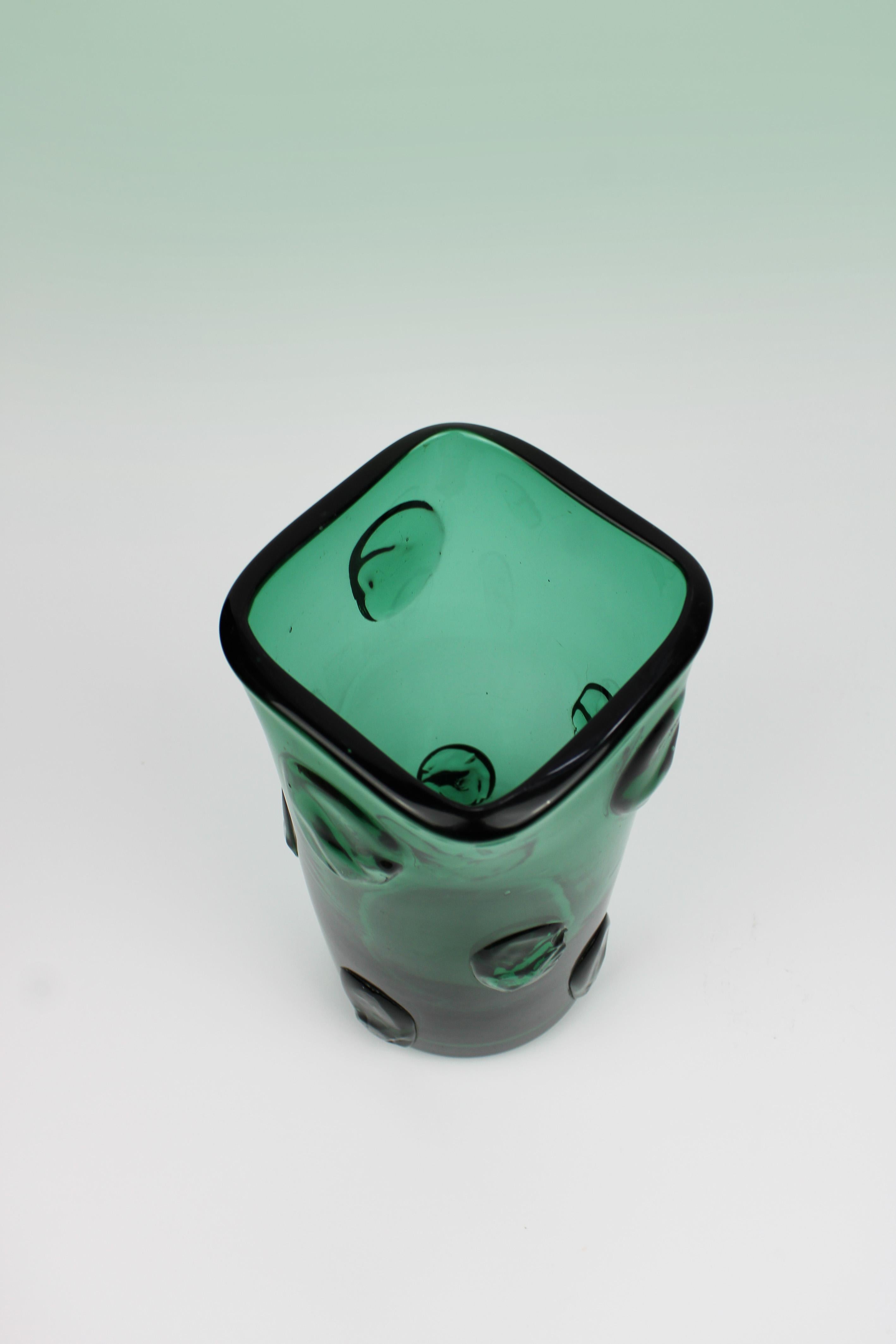 Introducing a stunning emerald green Empoli vase from Italy, crafted in 1960 from exquisite Murano glass. This unique piece features a distinctive design with a round base and a square top, complemented by hot-applied decorations on its surface. The