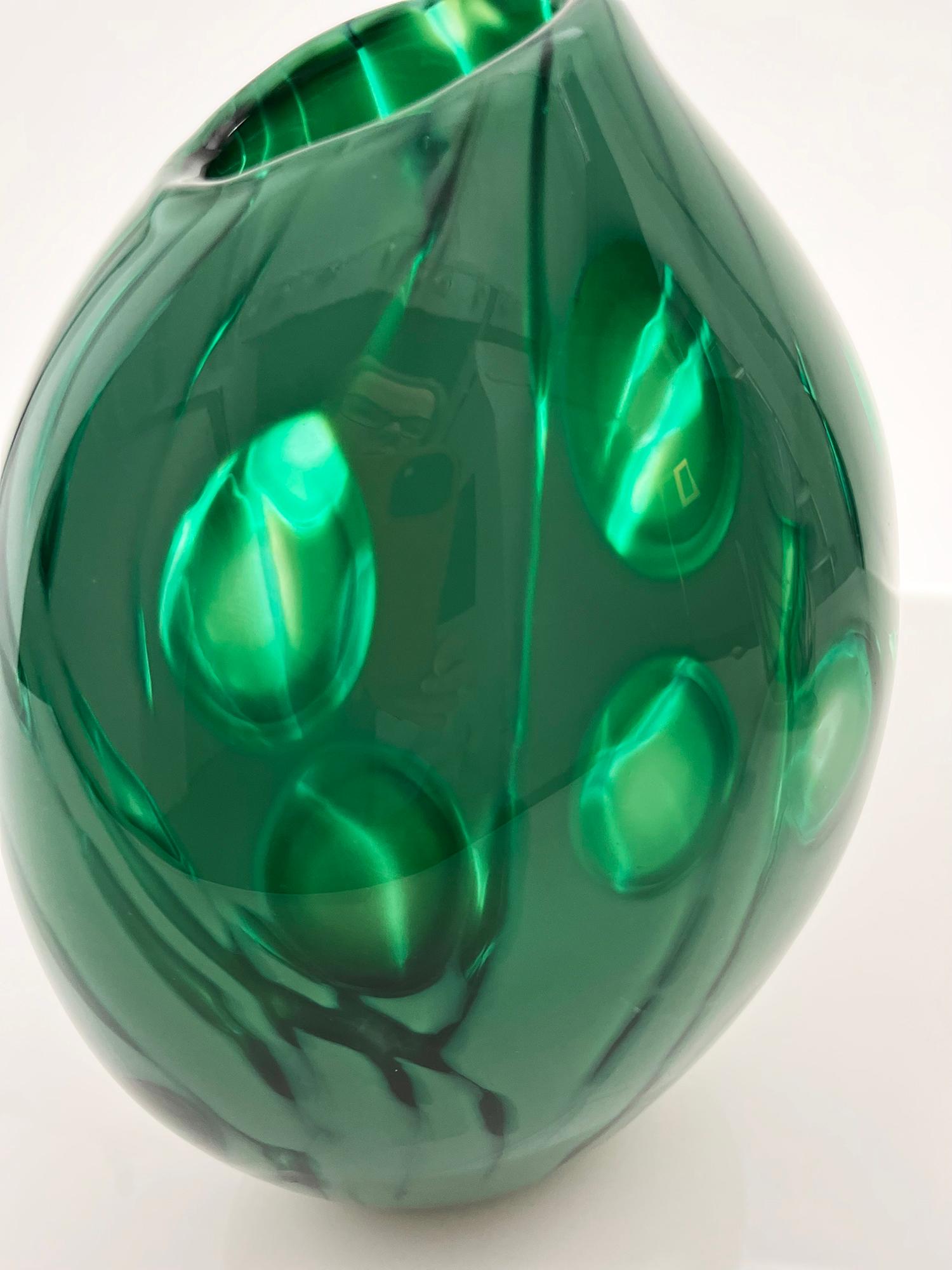 Emerald Green Glass pod is made using the Graal technique where a pattern or motif is cut through layers of glass on a smaller blank cup using diamond engraving wheels. The blank is then heated up and reblown, causing the cut marks to blend into the
