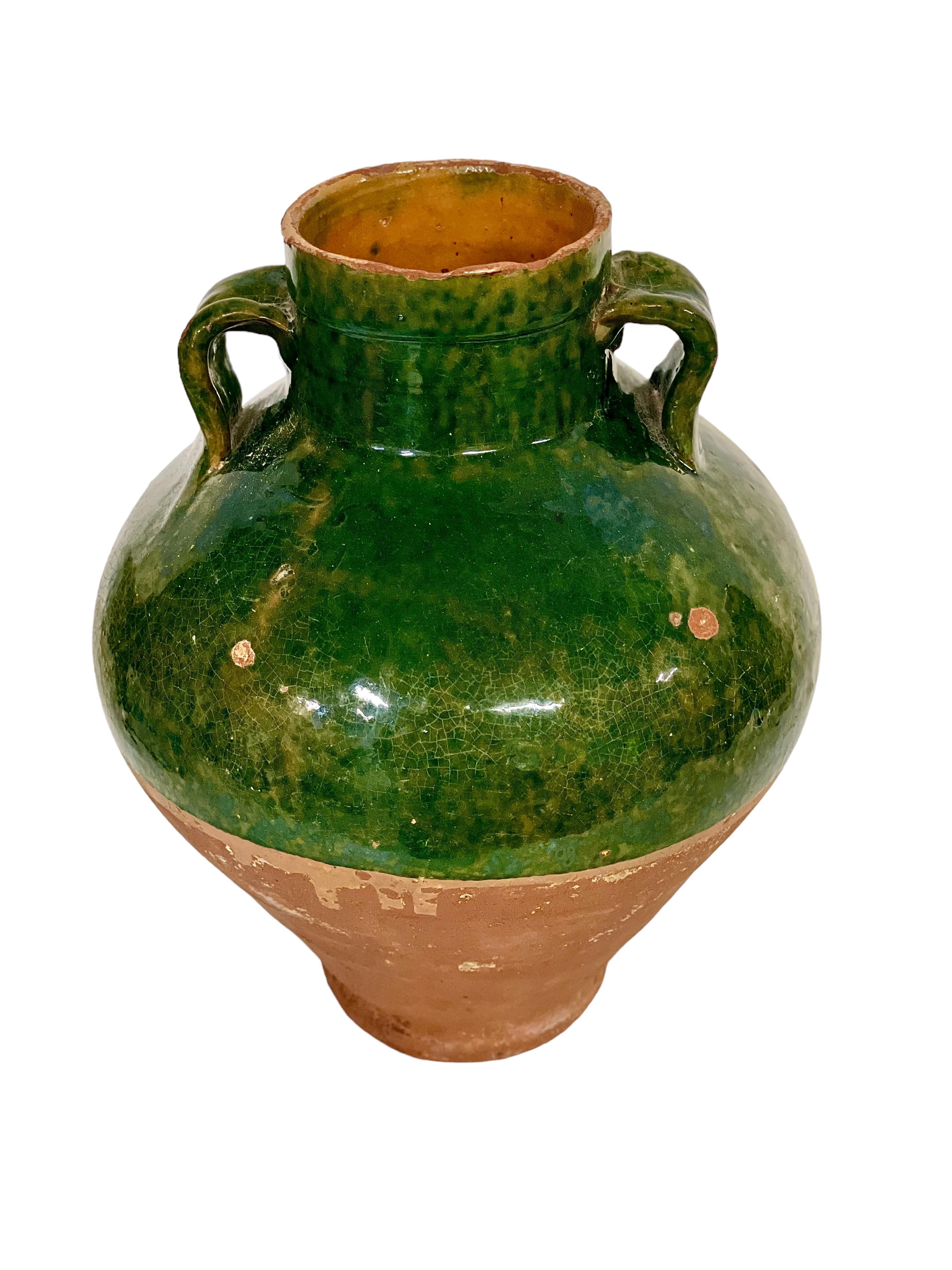 Dieser prächtige antike französische Terrakottatopf aus dem 19. Jahrhundert, halb glasiert in leuchtendem Smaragdgrün, diente ursprünglich als Haushaltsgefäß für die Aufbewahrung von Olivenöl. Innen vollständig verglast, ist nur die obere Hälfte der