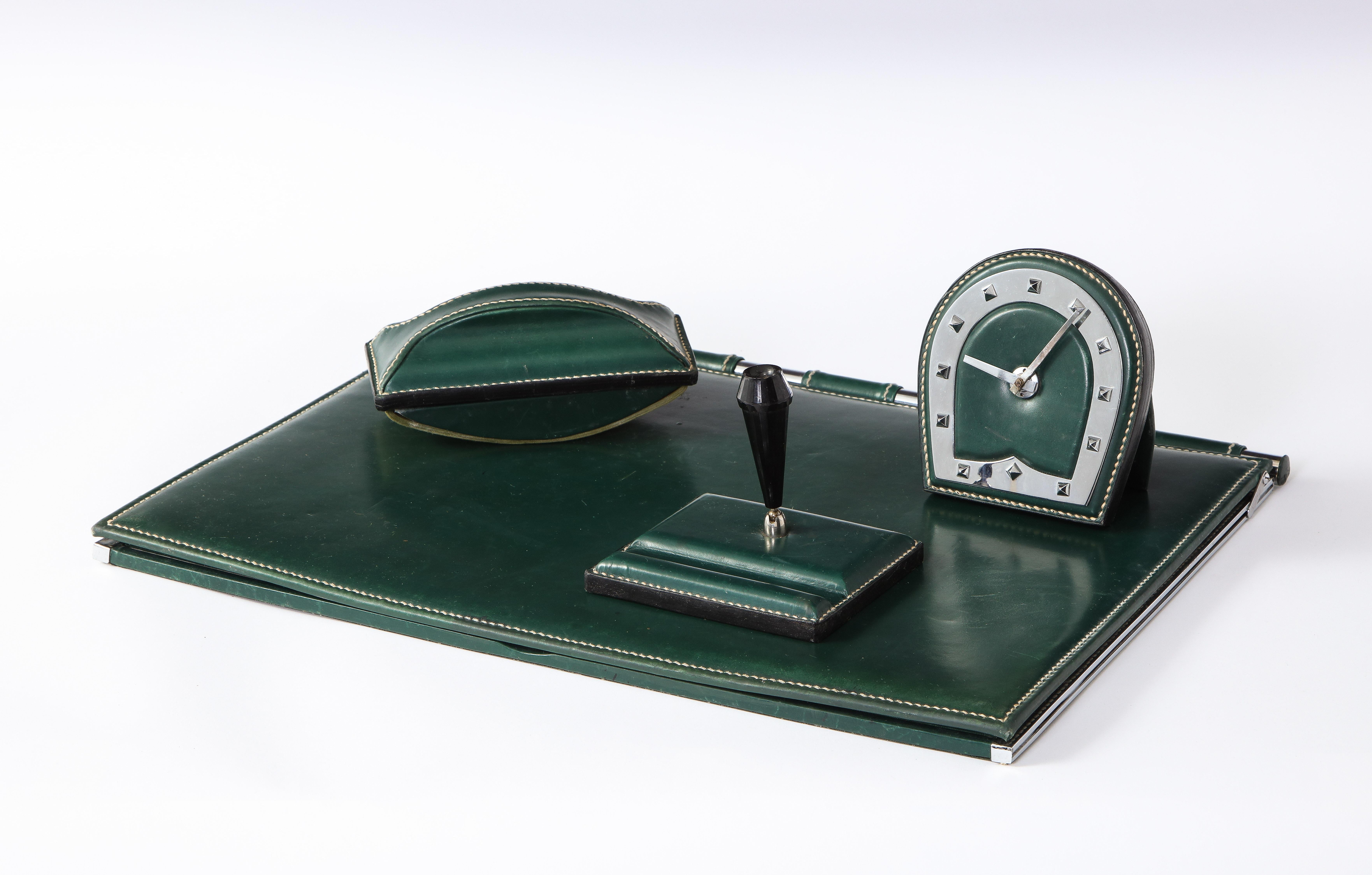 Desk set by Jacques Adnet comprises a desk mat a pen holder, ink blotter and a clock. All with signature Adnet saddle-stitch detail. In excellent vintage shape. Enquire about individual items sizes.