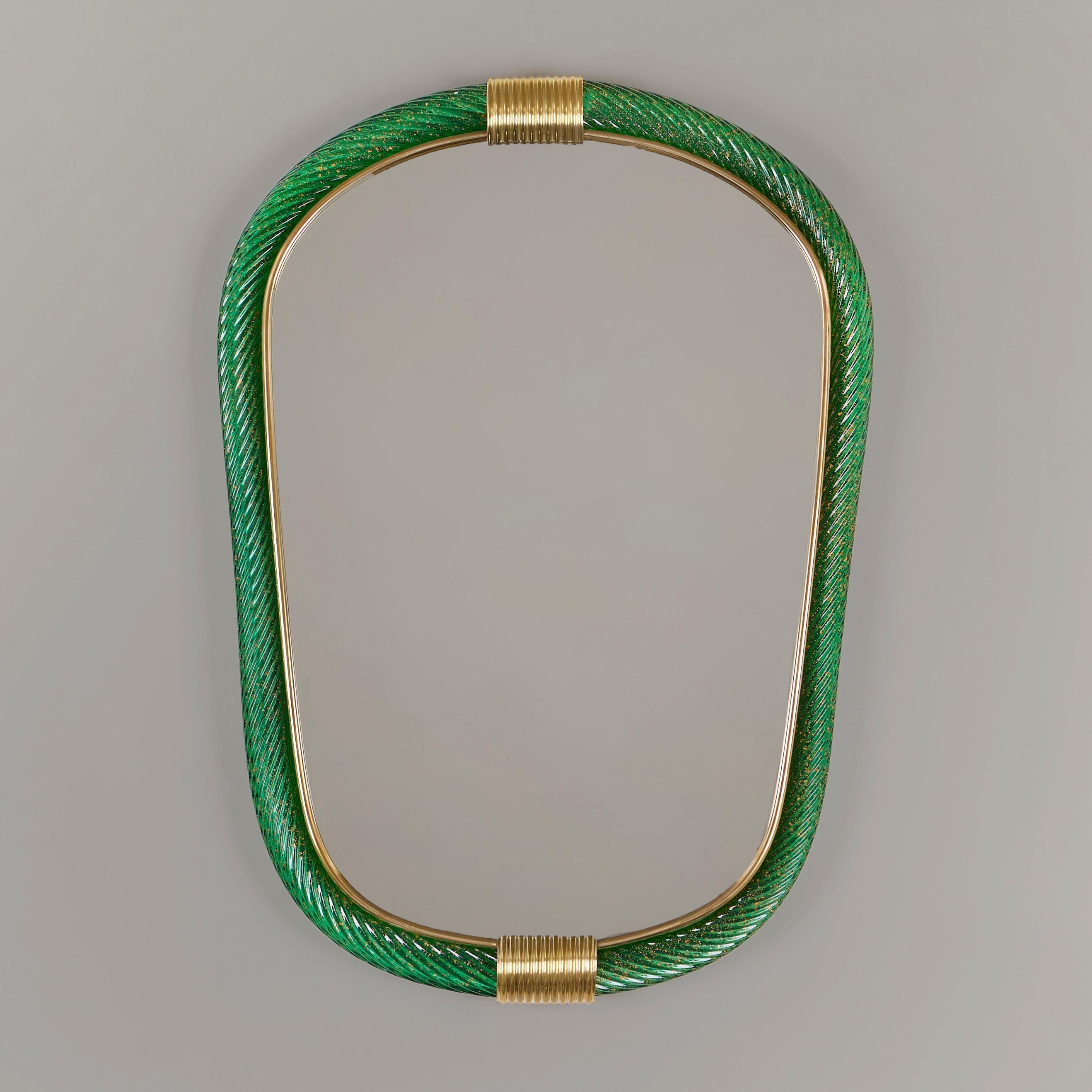 Eliptischer Spiegel aus mundgeblasenem Murano-Glas, smaragdgrün mit goldenen Flecken, oben und unten mit zwei kannelierten Messingspangen, der innere Rand mit schlankem Messingfilet ausgekleidet.

Auch in blassblau und blassrosa erhältlich
