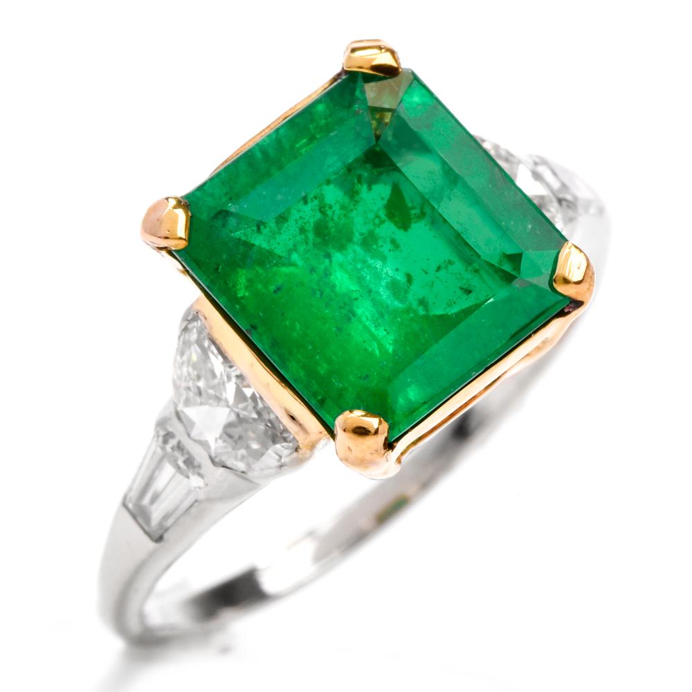 This emerald and diamond ring is crafted in solid platinum and 18k yellow gold. Displaying a centered emerald-cut genine emerald approx. 2.72 carats set in 18k yellow gold setting. Further embellished by four diamonds of halfmoon-cut and baguette
