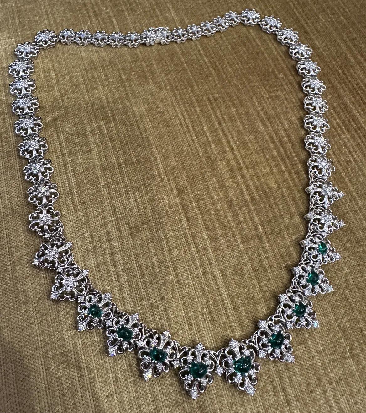 Emerald Heart Cabochon and Diamond Filigree Necklace in Platinum

Emerald and Diamond Necklace features 9 lively, deep green Heart shaped Emerald Cabochons with Round Brilliant Diamonds set in scrolled links in Platinum. Necklace is secured by a