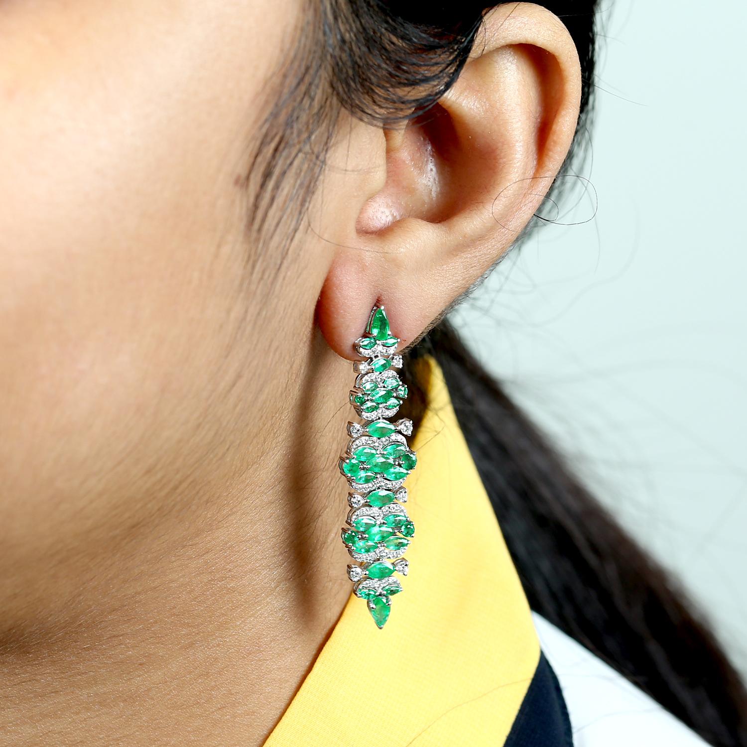 These emerald long dangle earrings are made from 14k white gold and feature diamonds. The emeralds are a rich, vibrant green color and are cut into a elongated shape that dangles elegantly from the ear. The diamonds add a touch of sparkle and shine