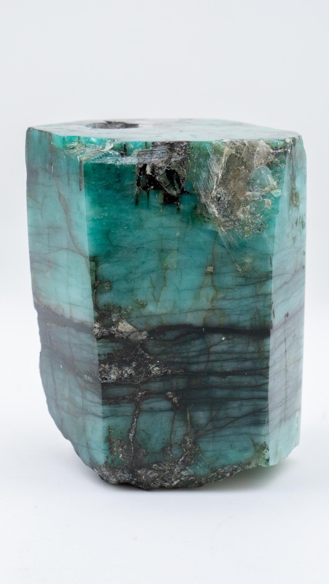 Raw polished emerald specimen. This is a beautiful stone with smoky rock crystal matrix that shimmers. This green semi precious stone, known for its rarity, was mined in Colombia and would make for a great gift for any stone enthusiast.