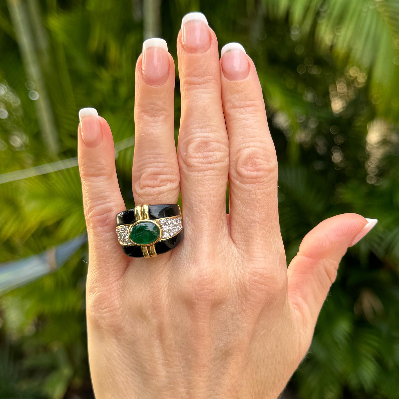 Fabulous emerald, diamond, and onyx cocktail ring handcrafted in 18 karat yellow gold. The band features a bezel set oval cabochon green emerald weighing approximately 4.00 carats, 24 round briliant cut diamonds weighing approximately 2.50 carat