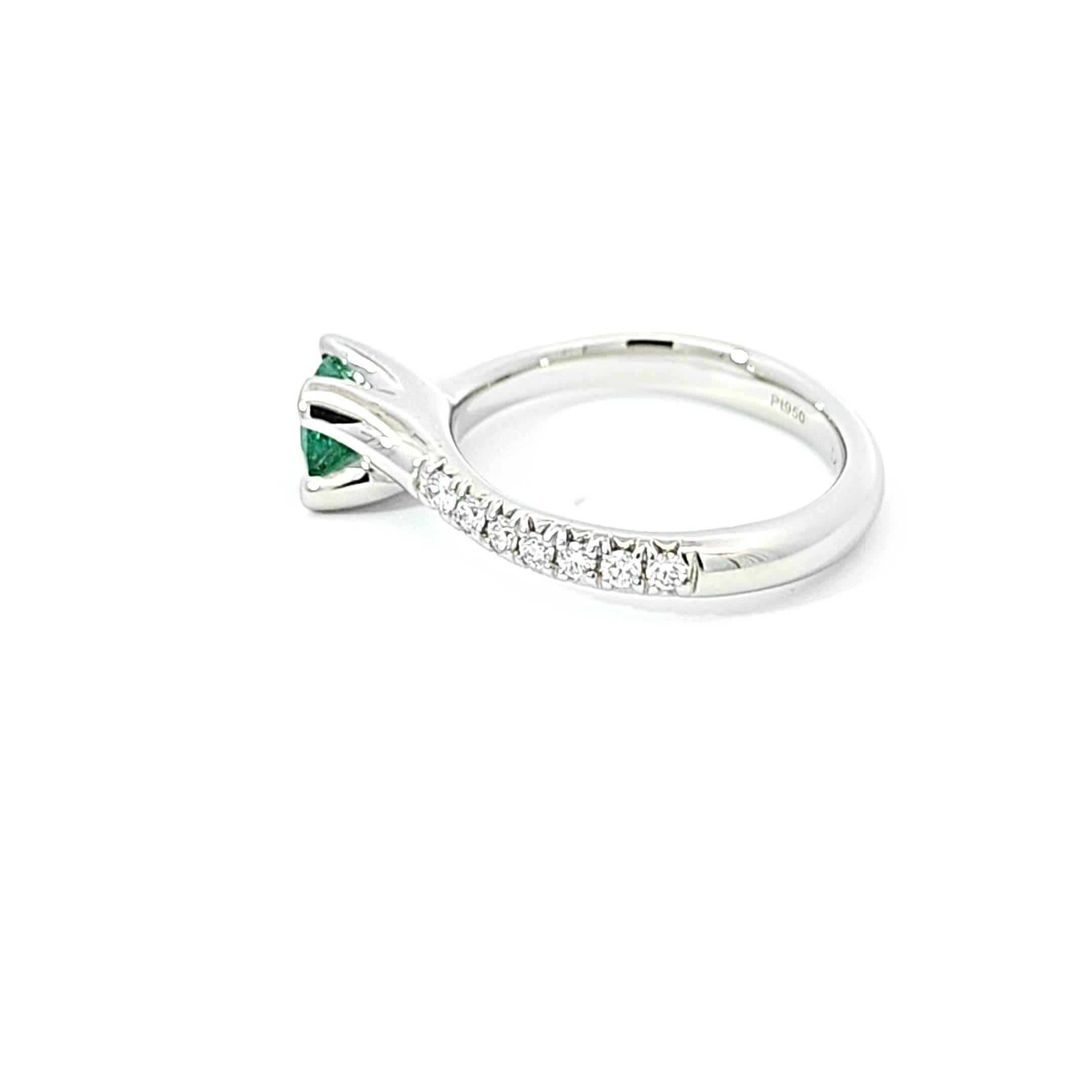 This striking platinum ring pays homage to historic elegance with its emerald and diamond adornments. The resplendent center emerald displays the entrancing green that has captivated royalty and connoisseurs for centuries. Its focal placement honors